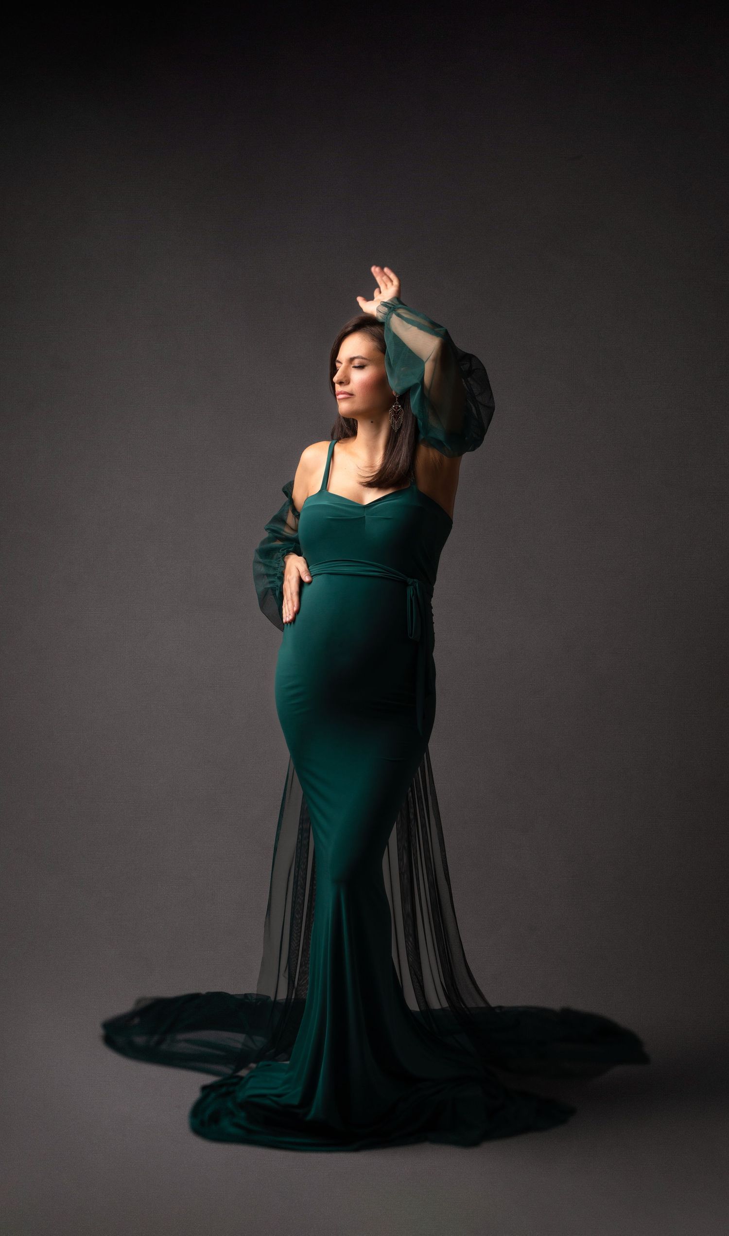 Elegant maternity portrait in emerald green velvet gown with flowing train. Dubai Photographer
