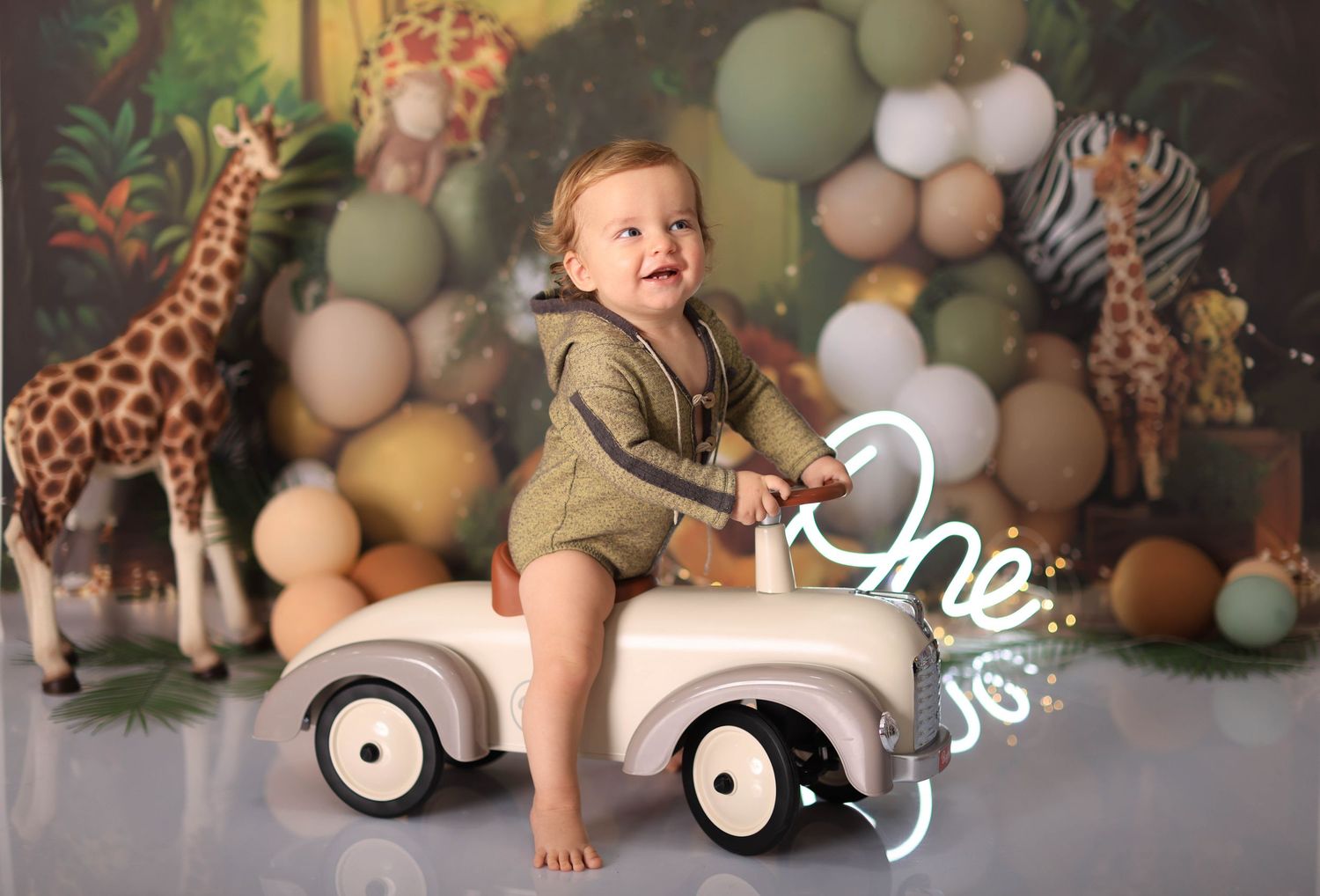 First birthday photoshoot setup with safari theme featuring balloons, stuffed giraffes, and jungle decorations. Dubai Photographer