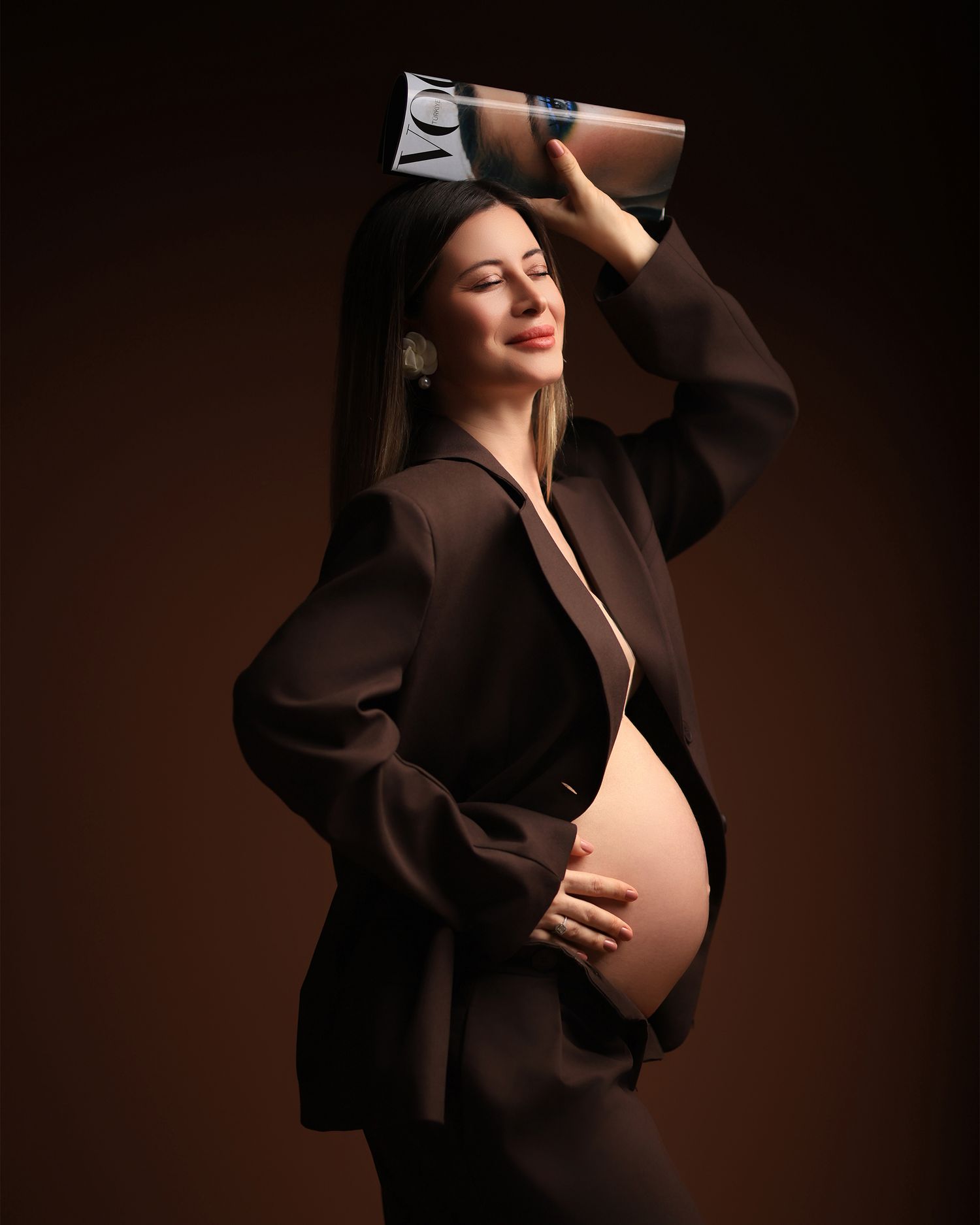Modern maternity photo with person in brown blazer against dark background. Dubai Photographer
