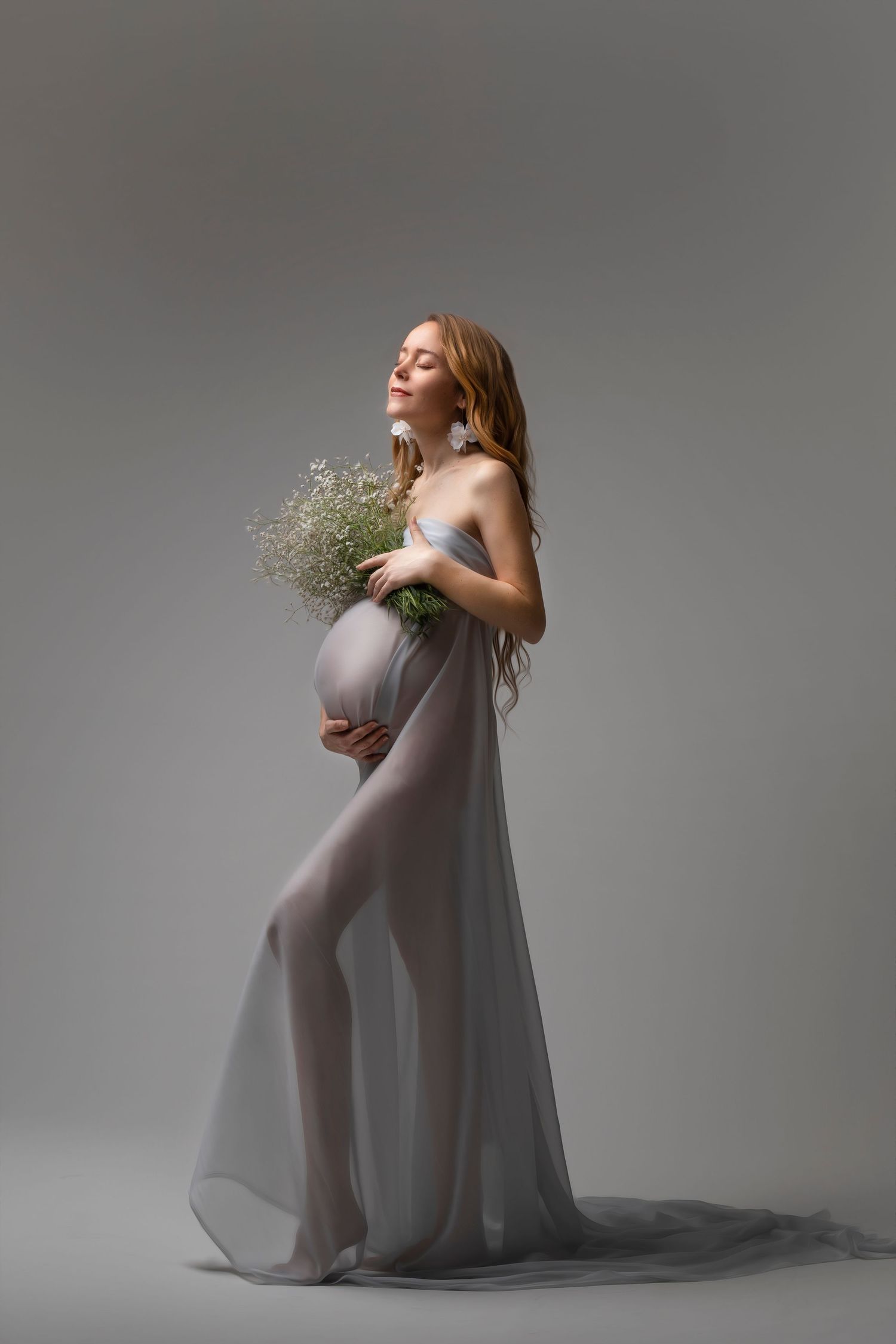 Dreamy maternity portrait with sheer grey gown and baby's breath bouquet.  Dubai Photographer