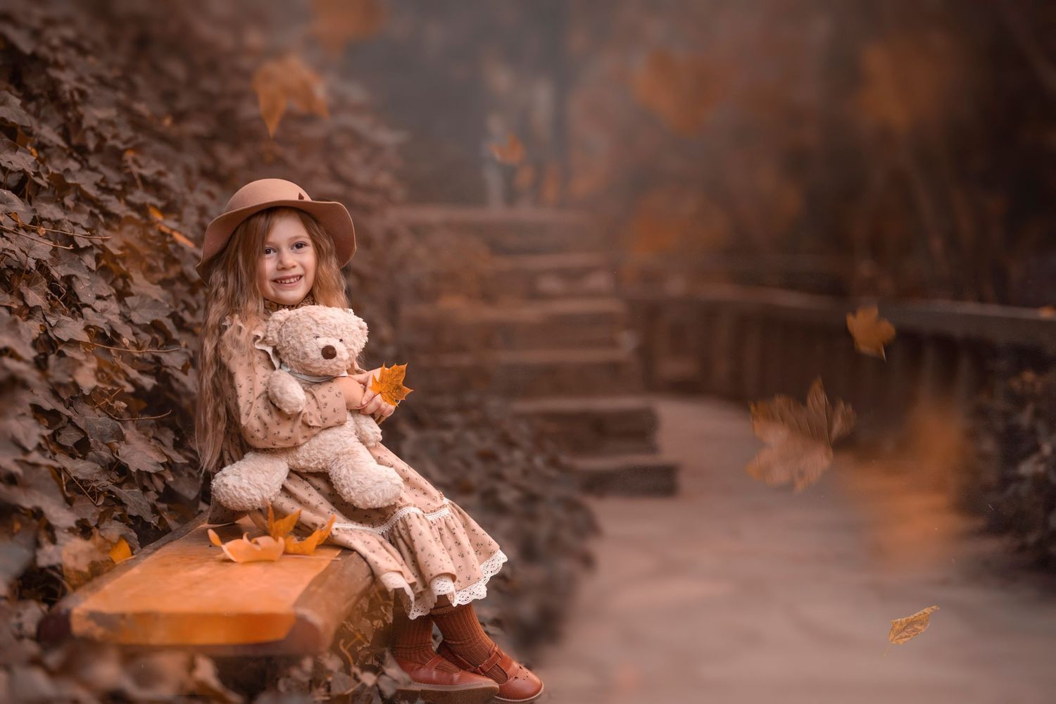 An autumn scene featuring a person sitting on steps with a teddy bear amid falling leaves. Dubai Photographer