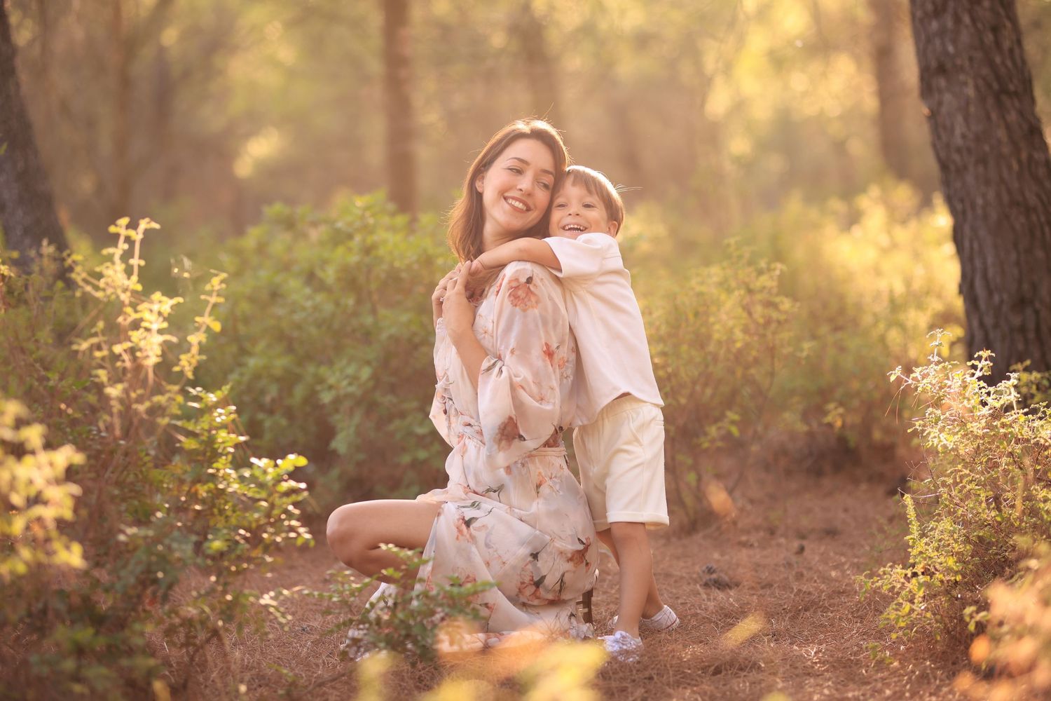 Two people share a tender moment on the grass during sunset in a wooded outdoor setting.Dubai Photographer
