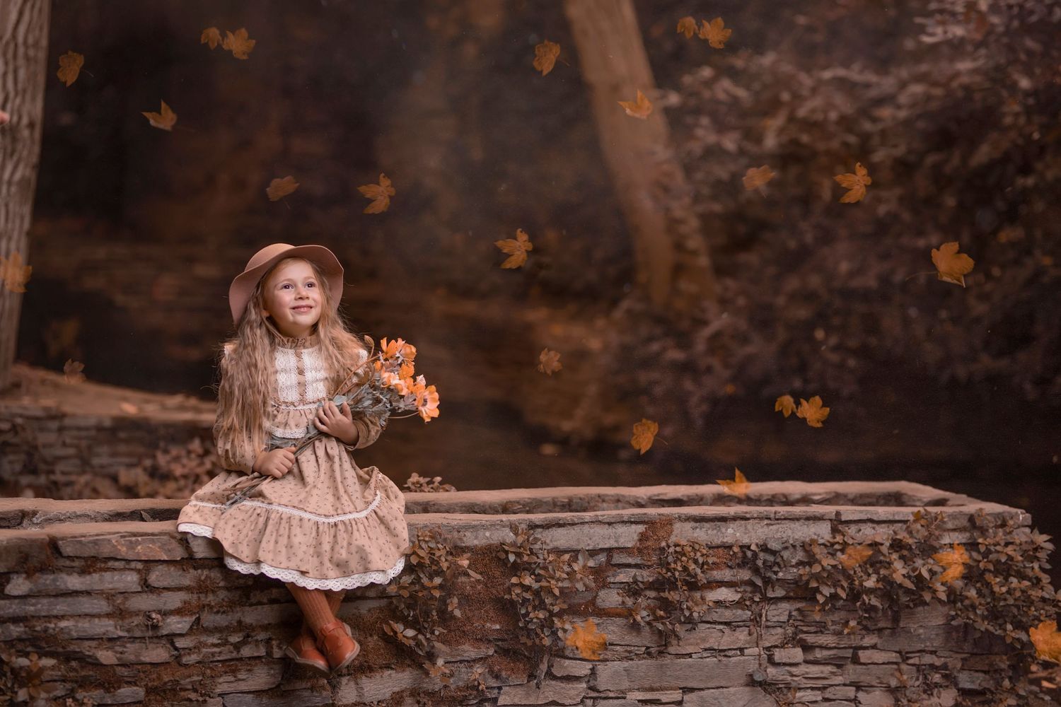 A vintage-styled autumn scene with a figure sitting on a stone wall holding a teddy bear as leaves fall around. Dubai Photographer