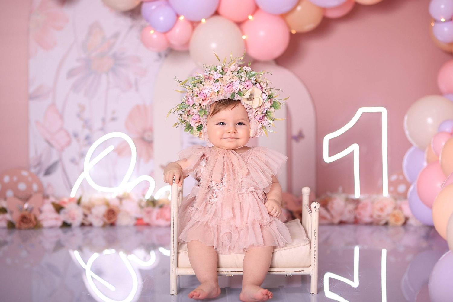 Pink and peach-colored balloons create a dreamy backdrop for a cozy first birthday celebration setting. Dubai Photographer