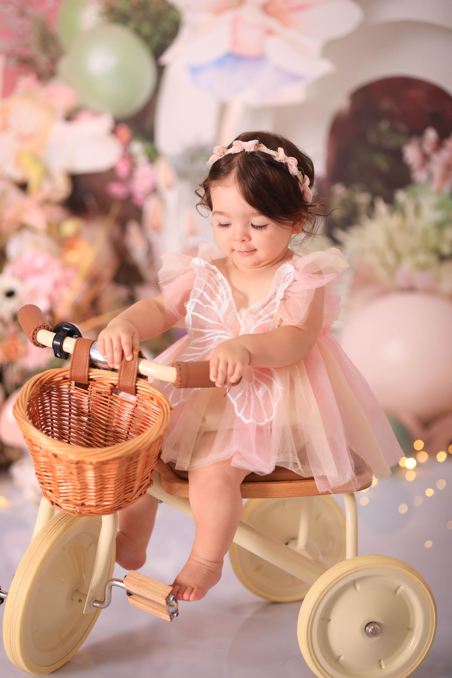 A dreamy photo series showing a child on a cream-colored vintage bicycle with wicker basket among pink floral decorations. Dubai Photographe