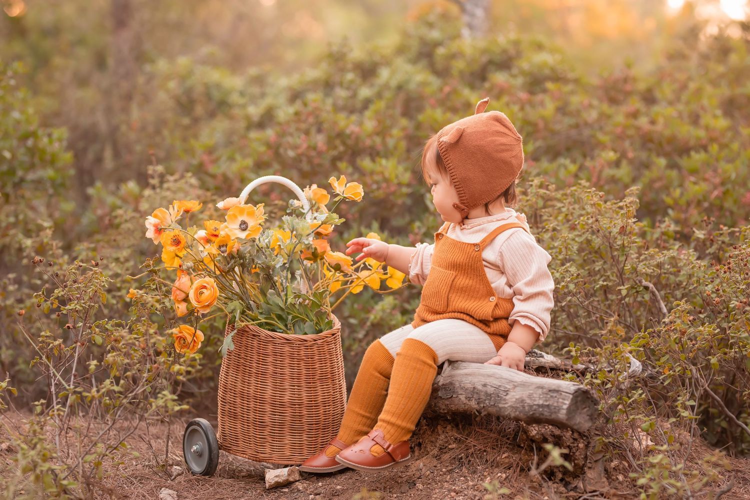 Child resting near wicker basket filled with orange flowers on rustic woodland path. Dubai Photographer
