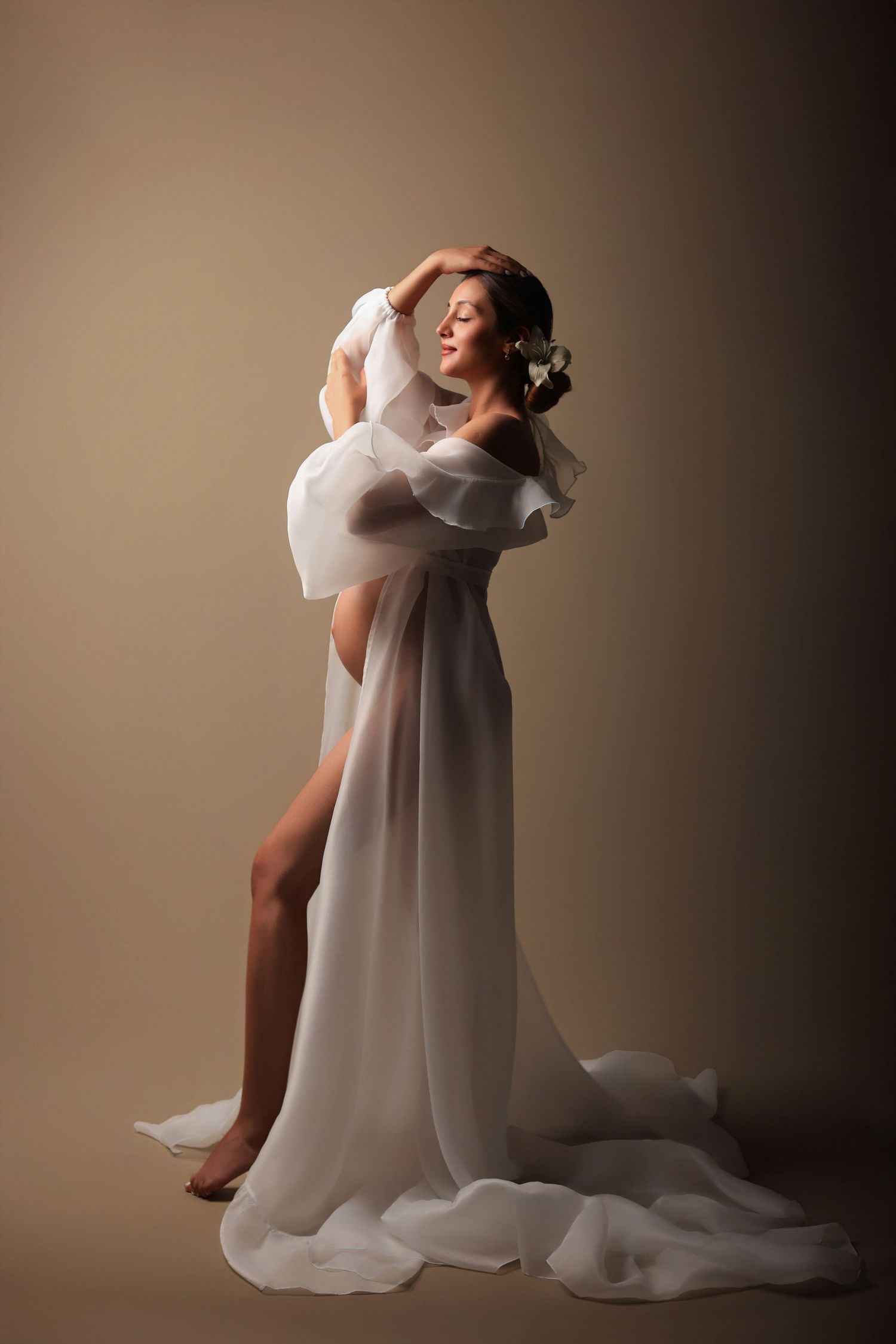Ethereal studio portrait of a graceful dancer in flowing white gown with dramatic leg pose and delicate movement.Dubai Photographer