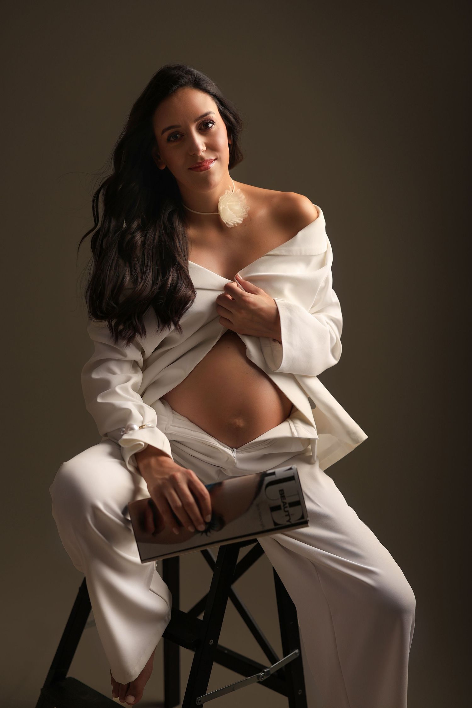 Artistic portrait of someone posing on a stool wearing an unbuttoned white shirt and pants in dramatic lighting. Dubai Photographer