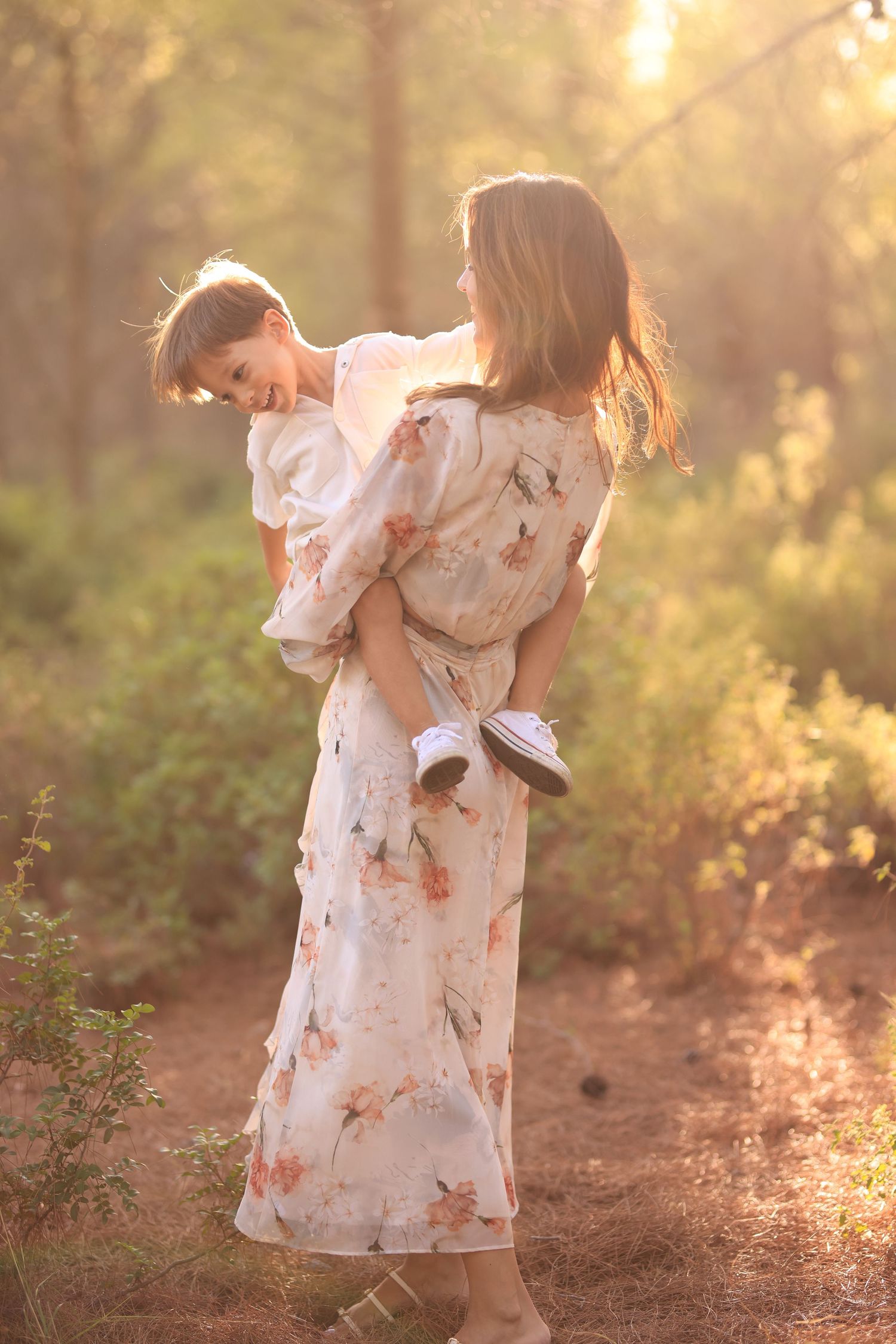Child in white floral dress twirls gracefully at sunset in a wooded setting creating dreamy golden hour portraits.Dubai Photographer