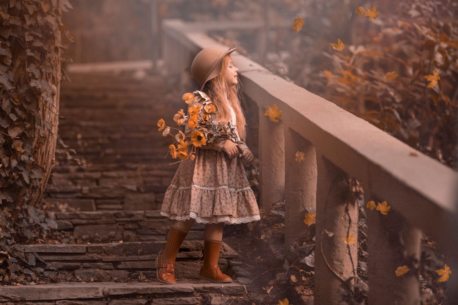 A warm-toned autumn portrait on stone steps with orange flowers and natural lighting. Dubai Photographer