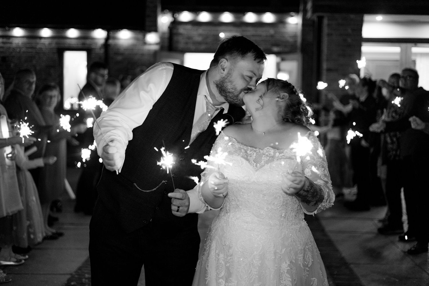 Wedding couple shares romantic dance under string lights at evening reception.
