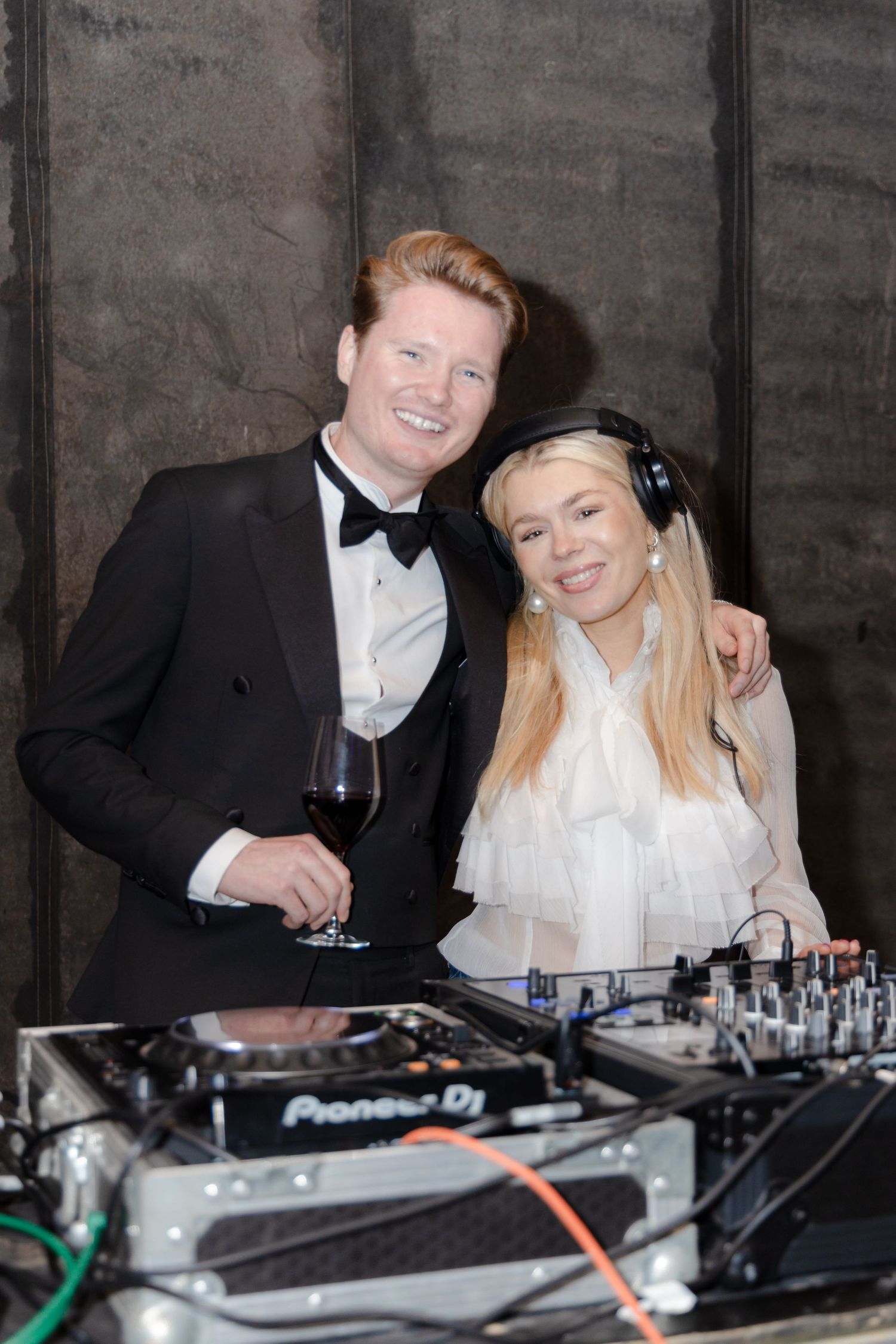 DJ booth setup with formal-dressed attendees enjoying music at an event.