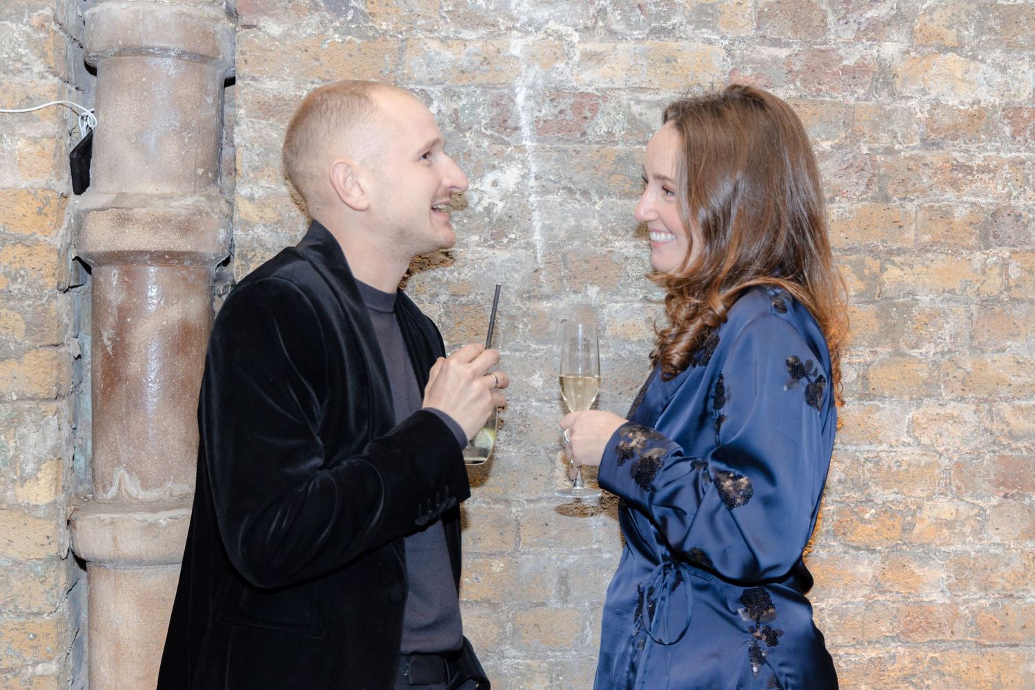 Couples sharing intimate conversations against a rustic stone wall backdrop.