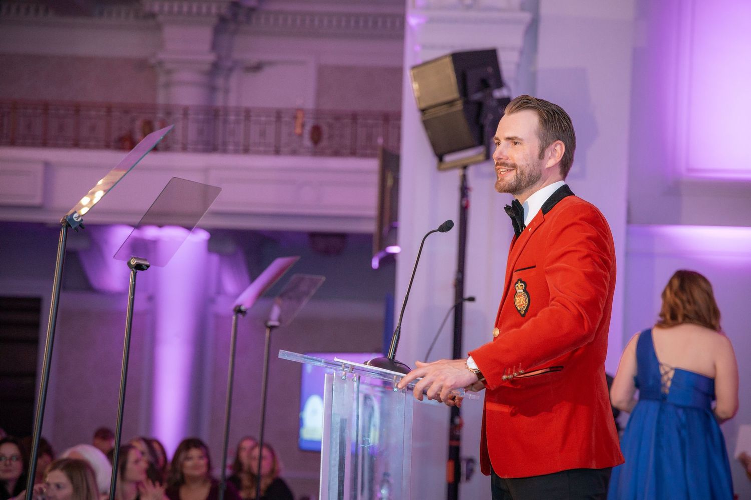 Elegant ballroom setup for awards ceremony with purple accent lighting and presentation podium.