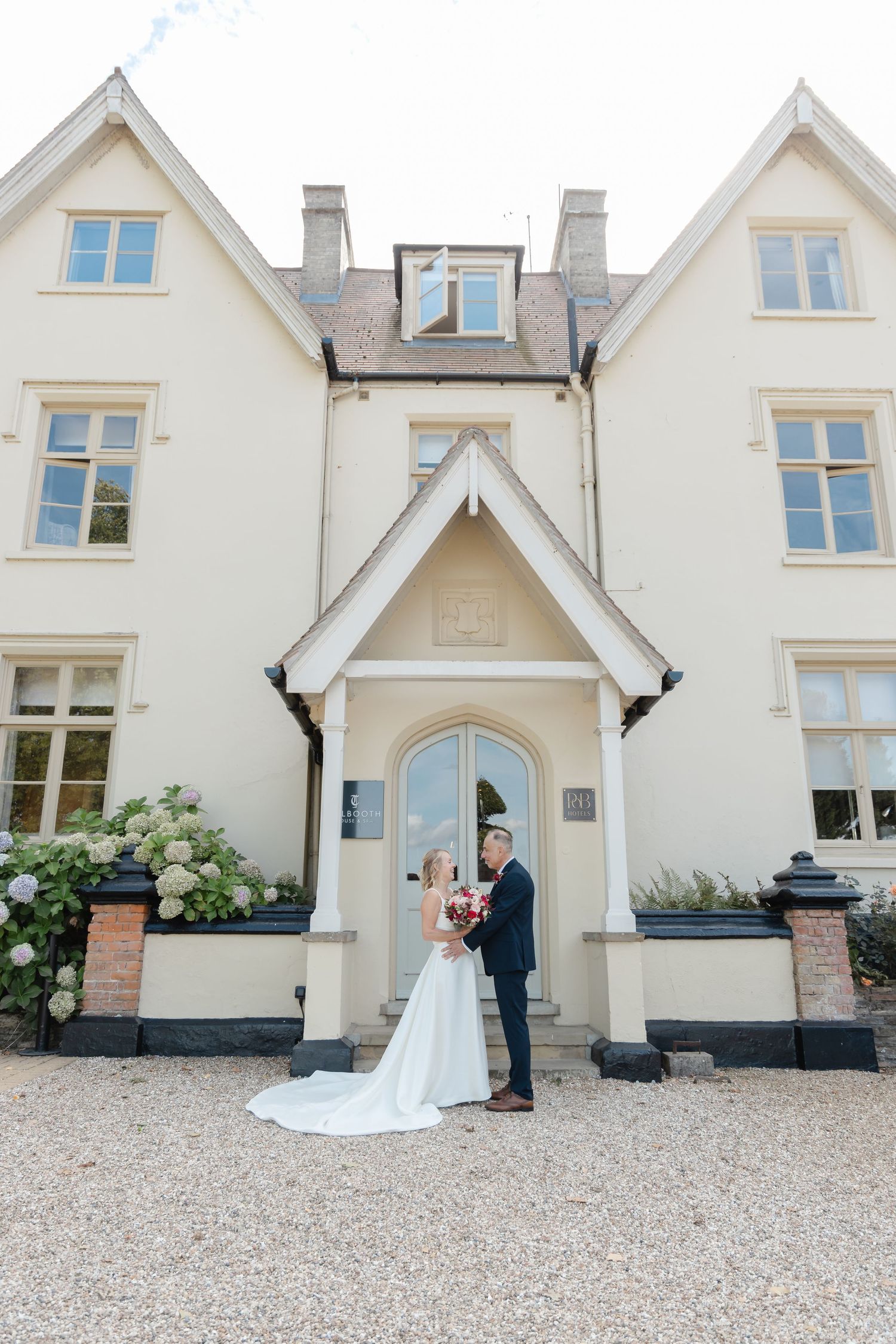 Couple poses for romantic wedding photos in front of a charming white manor house.