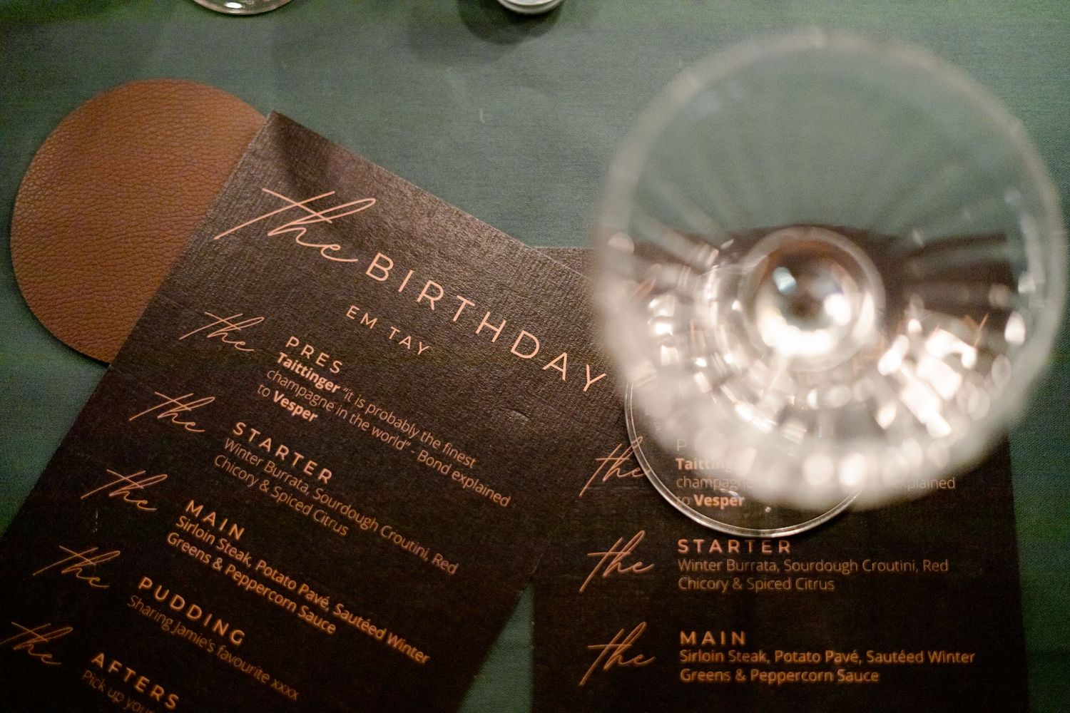 Birthday dinner menu card with wine glass in soft focus.