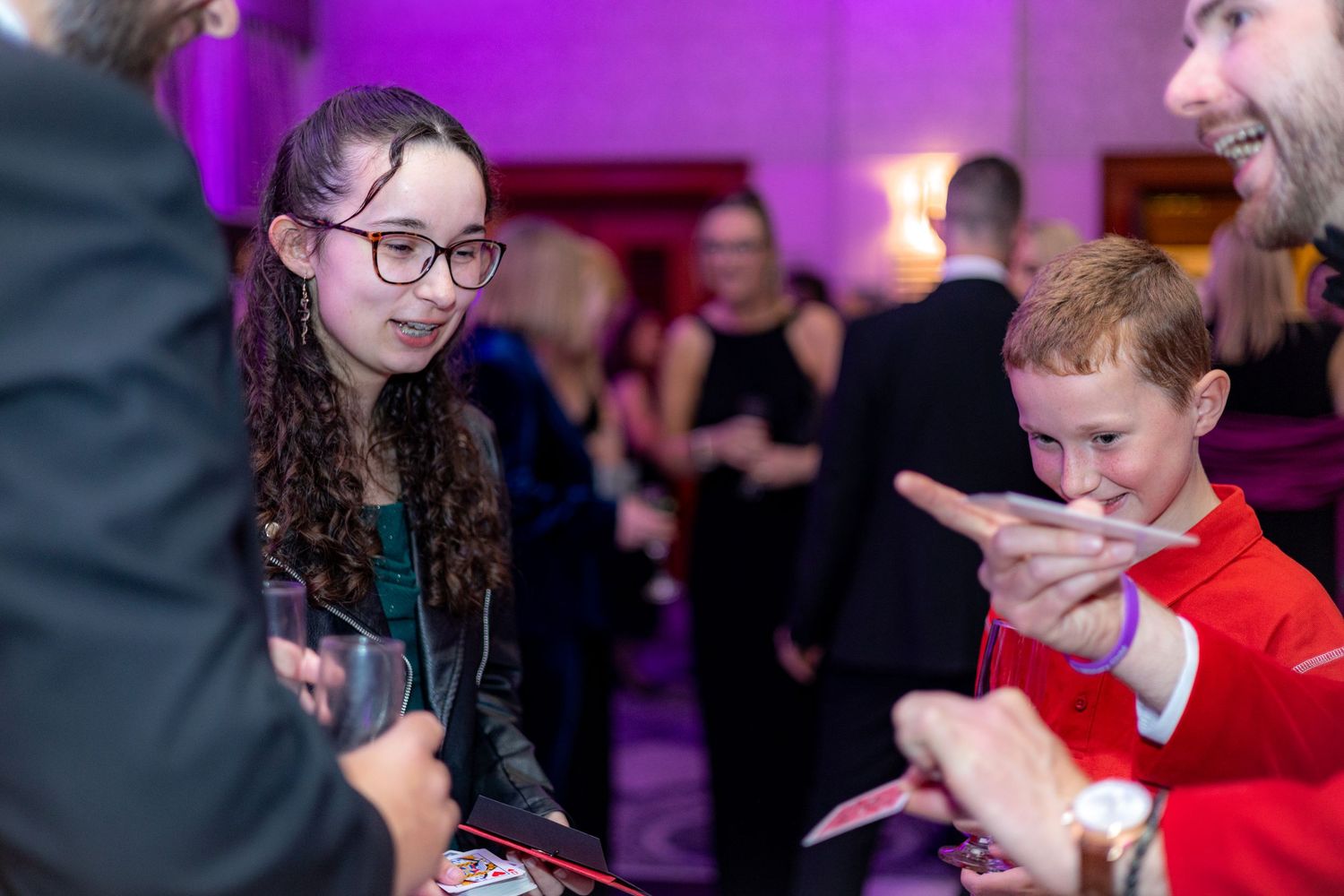 Event participants interacting during celebration with purple ambient lighting.