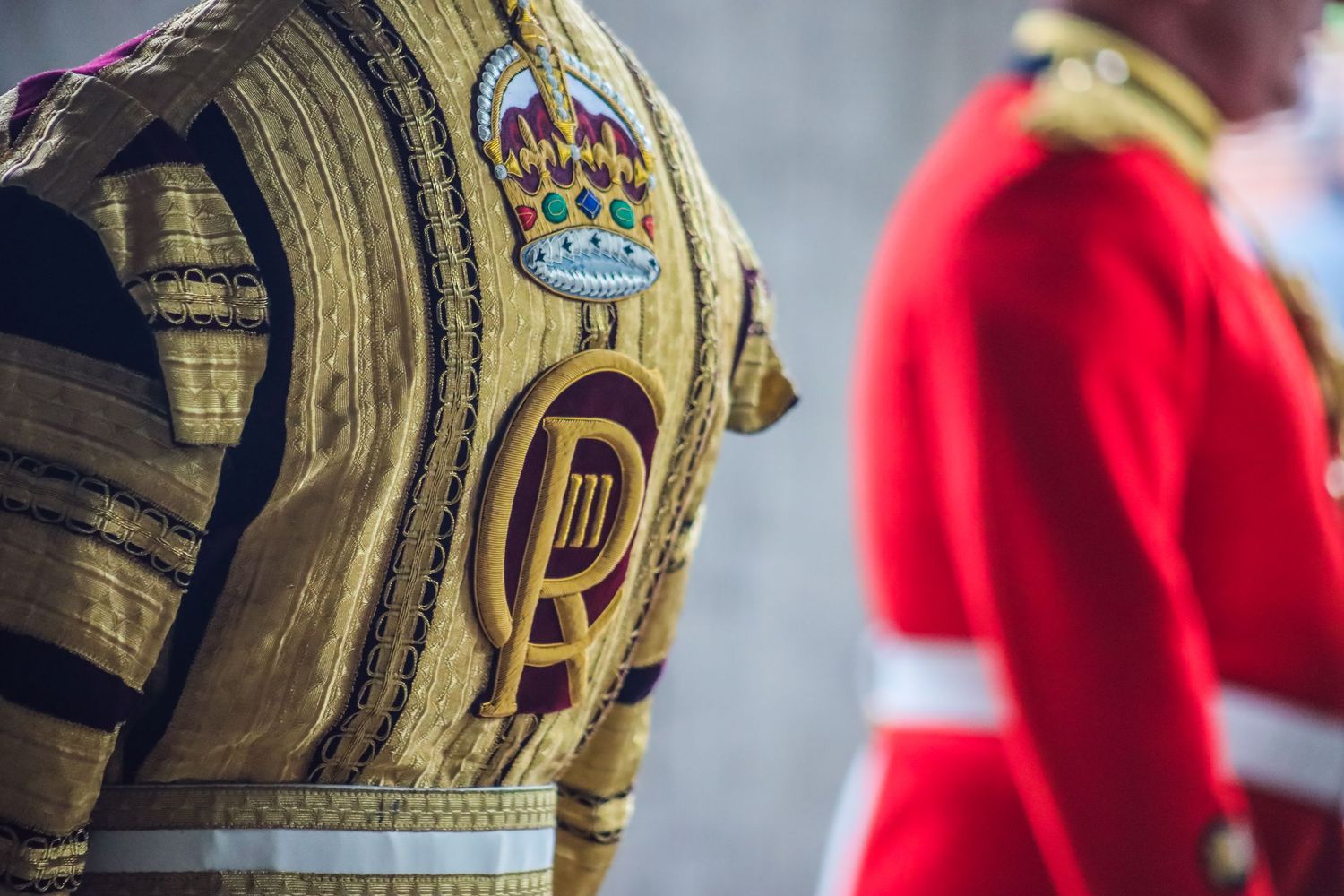 Close-up detail of gold military uniform embellishments with red background.