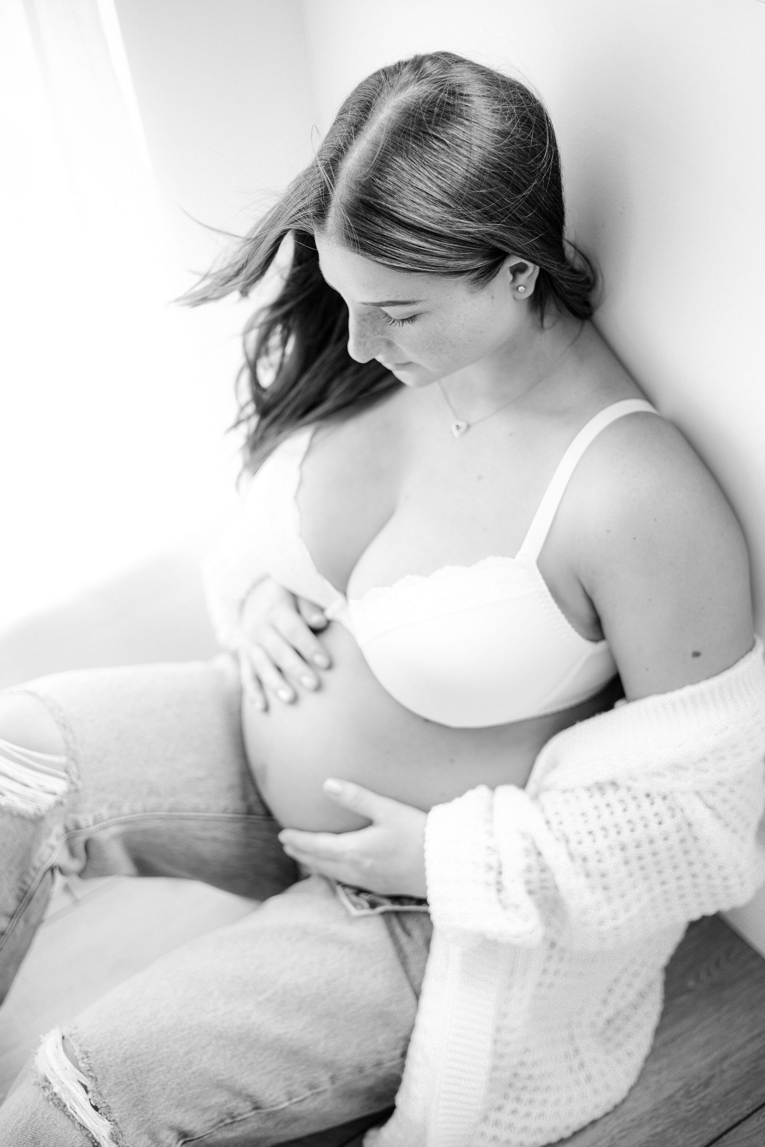 Intimate black and white maternity photos with soft lighting and white textured blanket.