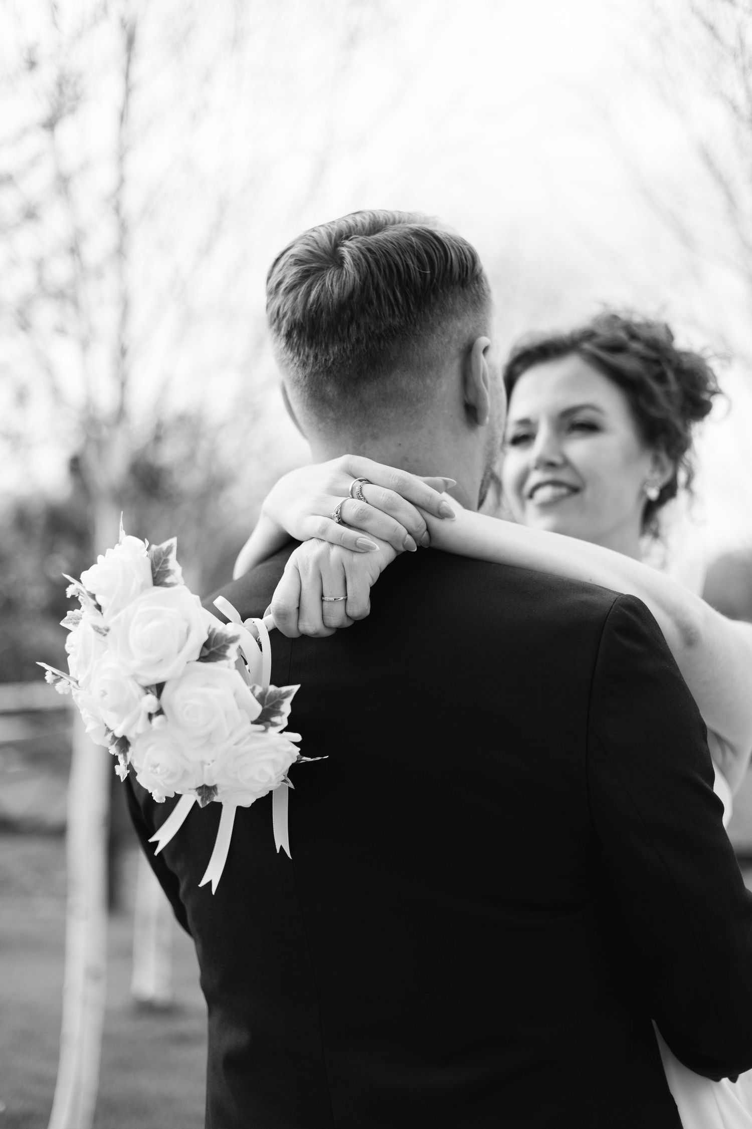 Black and white wedding portrait series showing intimate moments between newlyweds with white floral boutonniere.