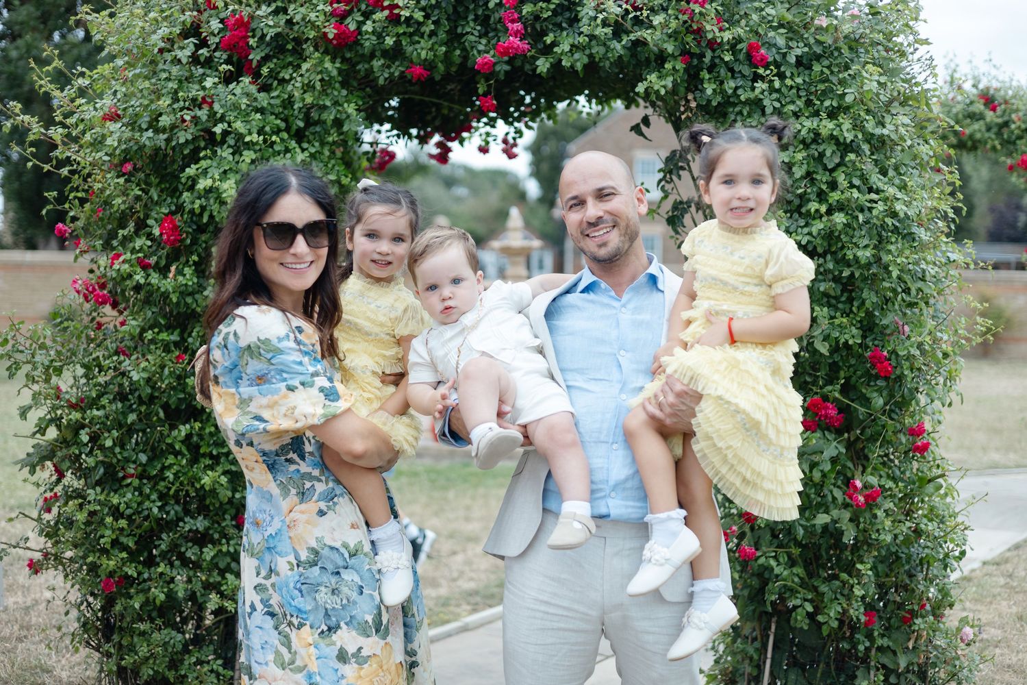 Group poses together under a blooming rose arbor in a garden setting.