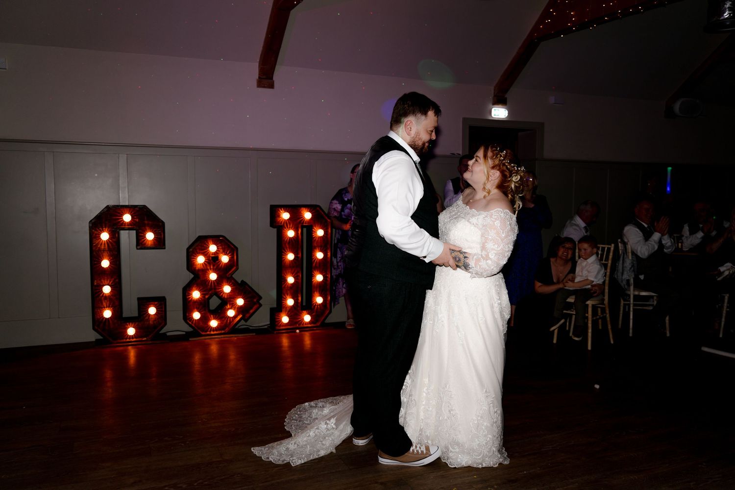 Romantic first dance moments captured in a dimly lit reception space.