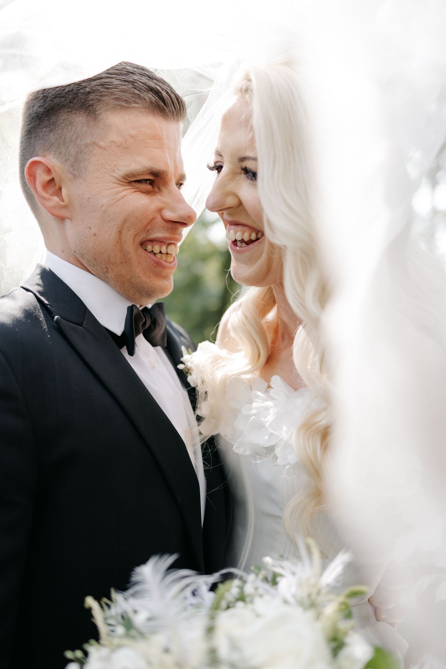 Romantic wedding couple sharing intimate moments under a white veil.