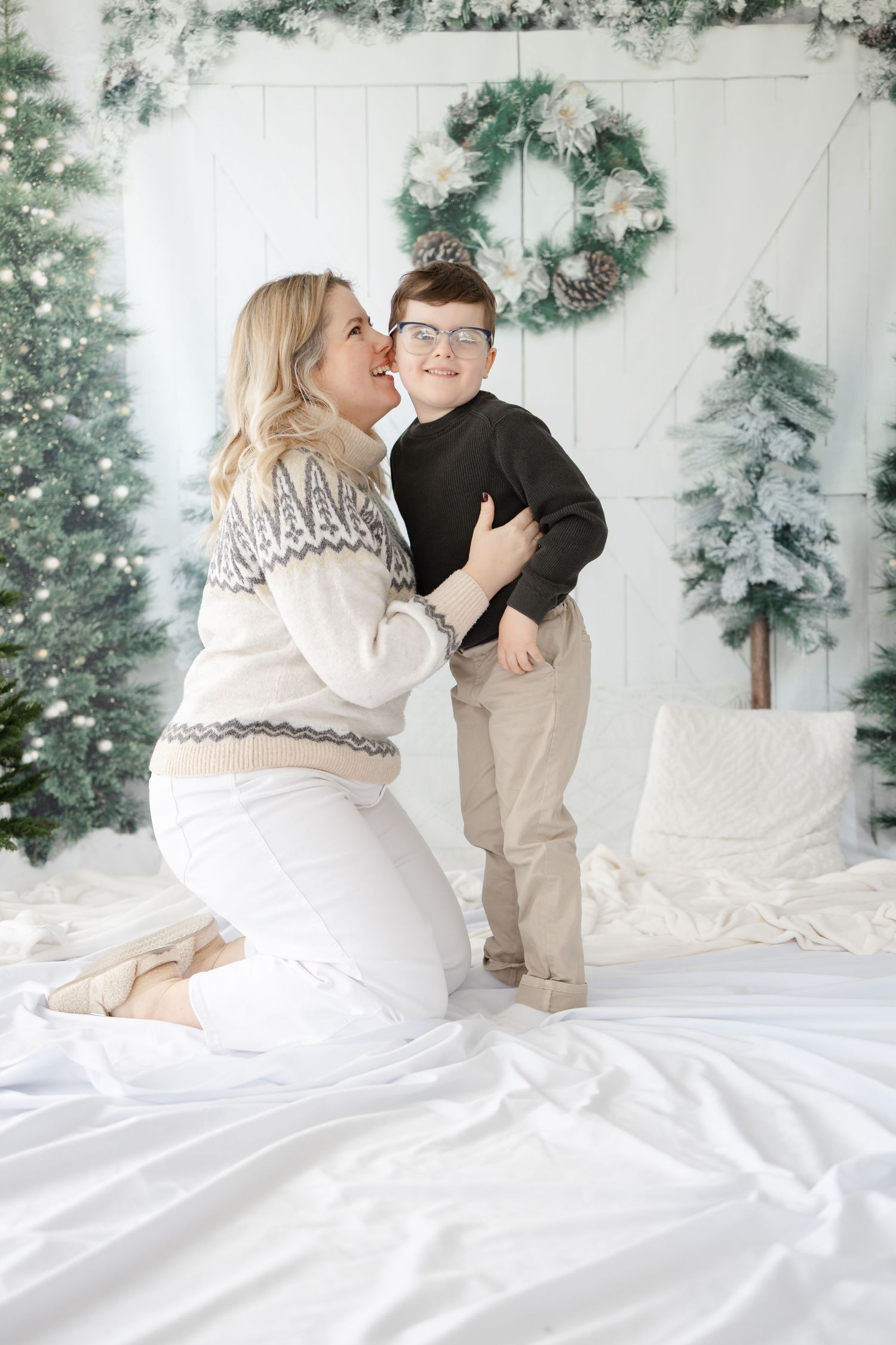 A touching moment between parent and child during a winter-themed photo session with holiday decorations.