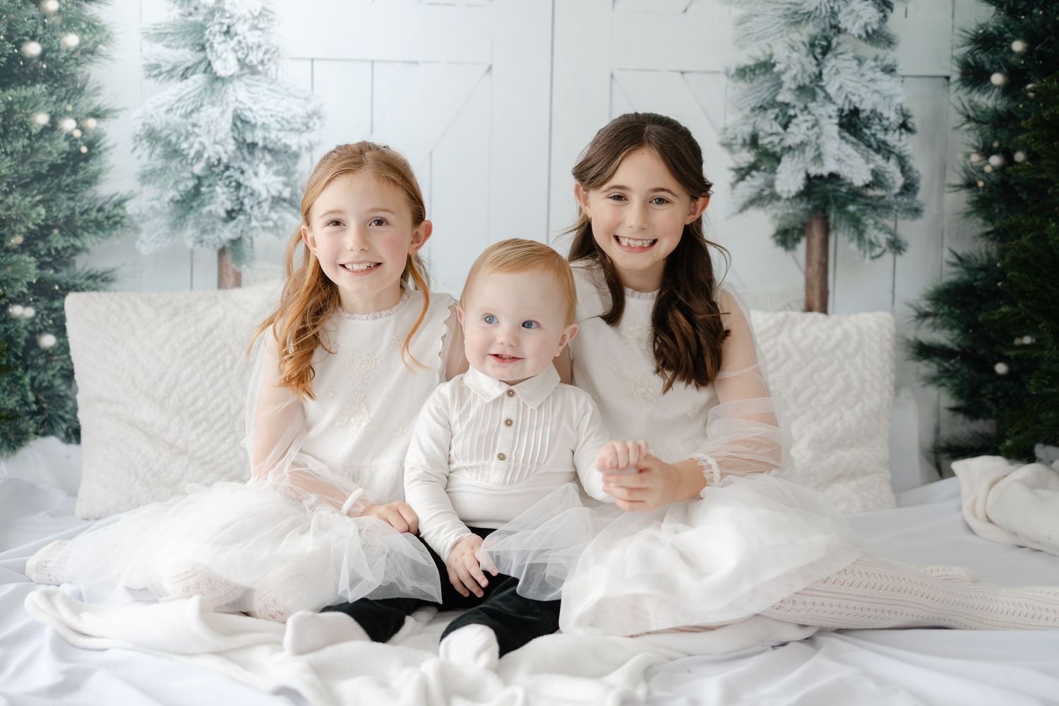 Family portrait session in white outfits against a snowy winter setting.