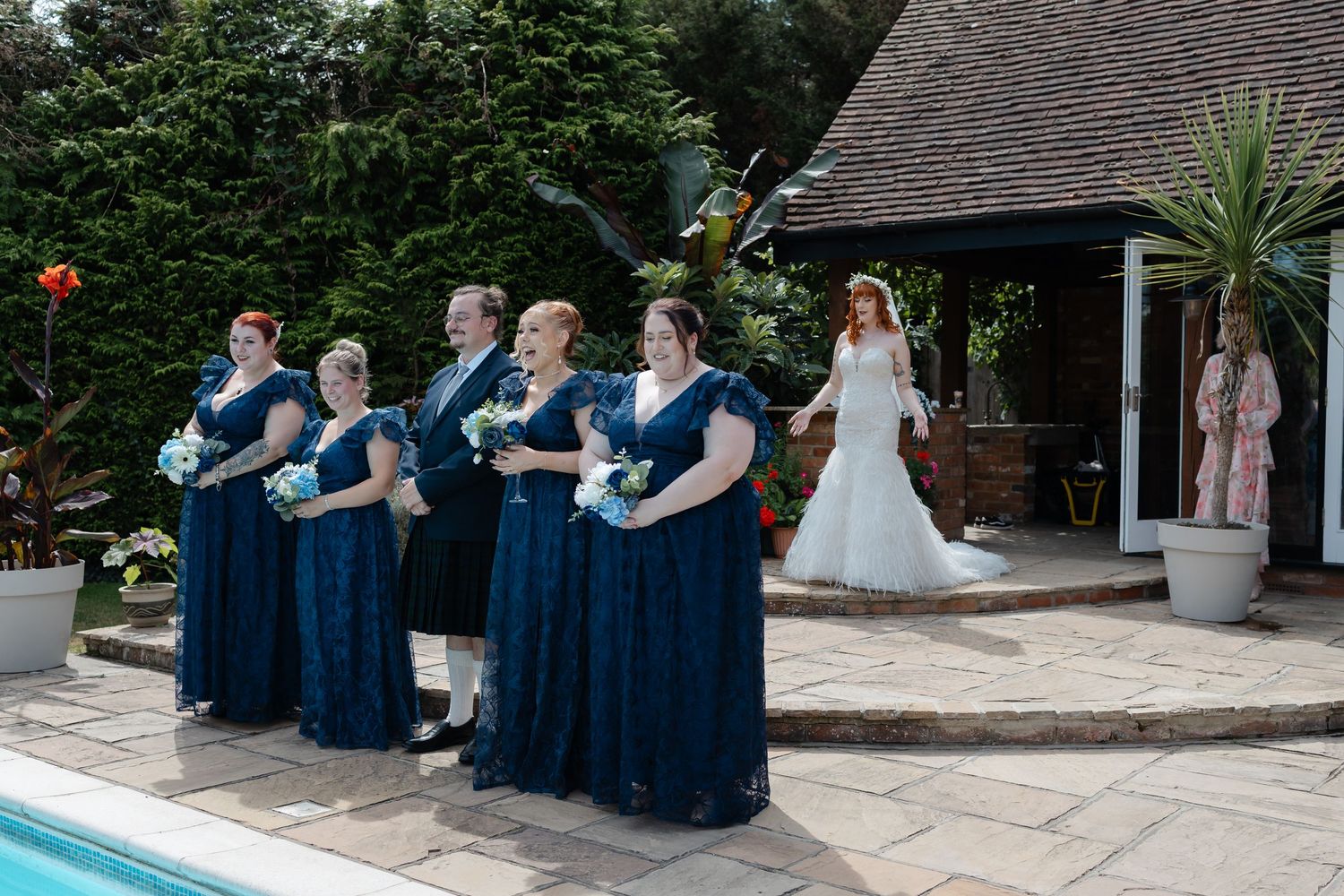 Wedding party gathered outdoors wearing navy blue and white formal attire.