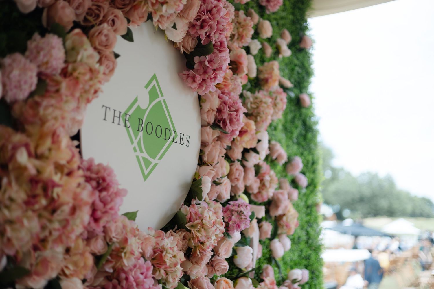 Floral wall installation featuring pink and white roses with greenery.