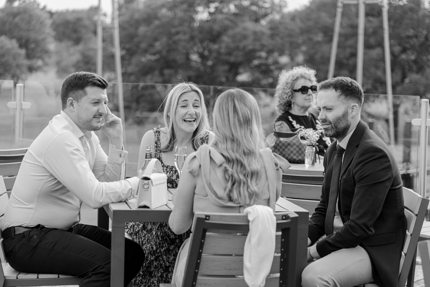 Friends gather around an outdoor table for drinks and conversation.