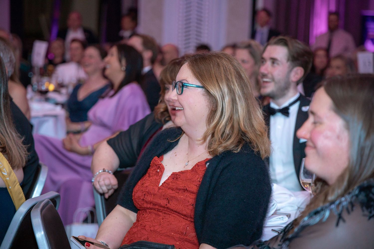 Audience members showing joyful reactions during a formal evening event.