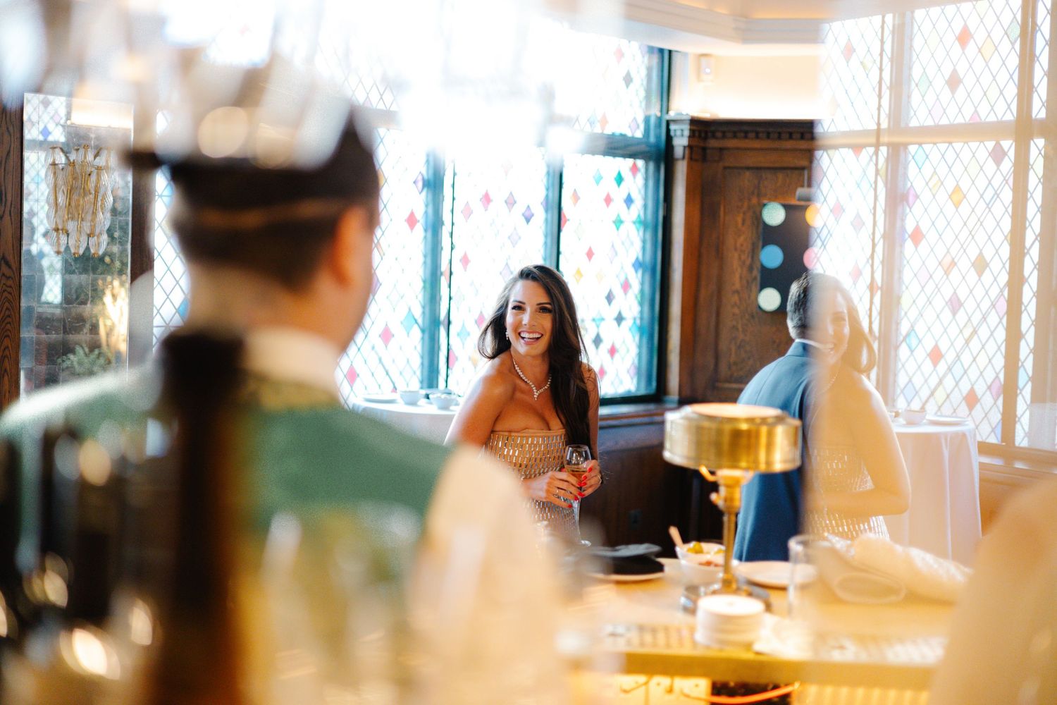 Wedding guests embrace warmly in an elegant venue with soft lighting and a bar in the background.