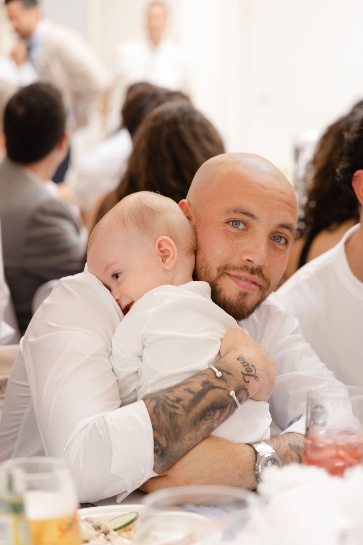 Two people share an intimate moment at a formal event with white table settings.