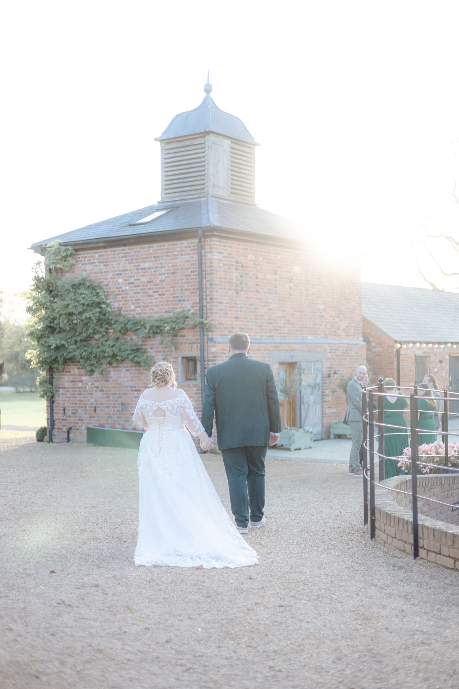 Wedding couple walking outside a brick church building at sunset.