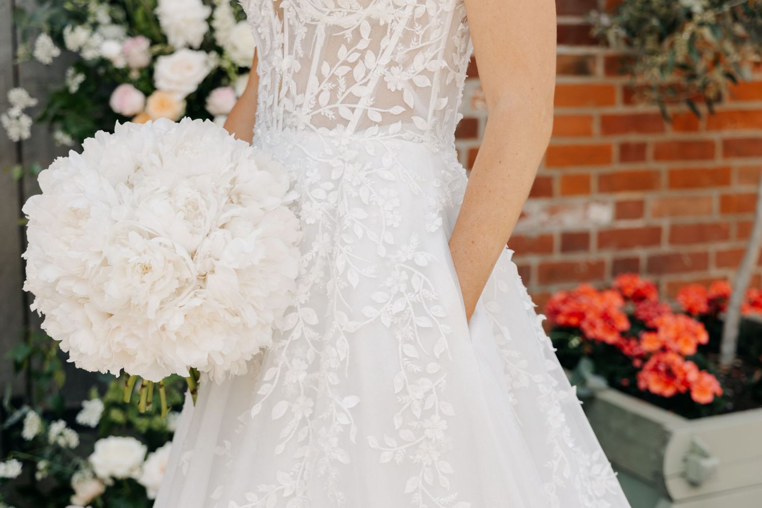 Detail shots of intricate white wedding dress with lace and beading against brick background.