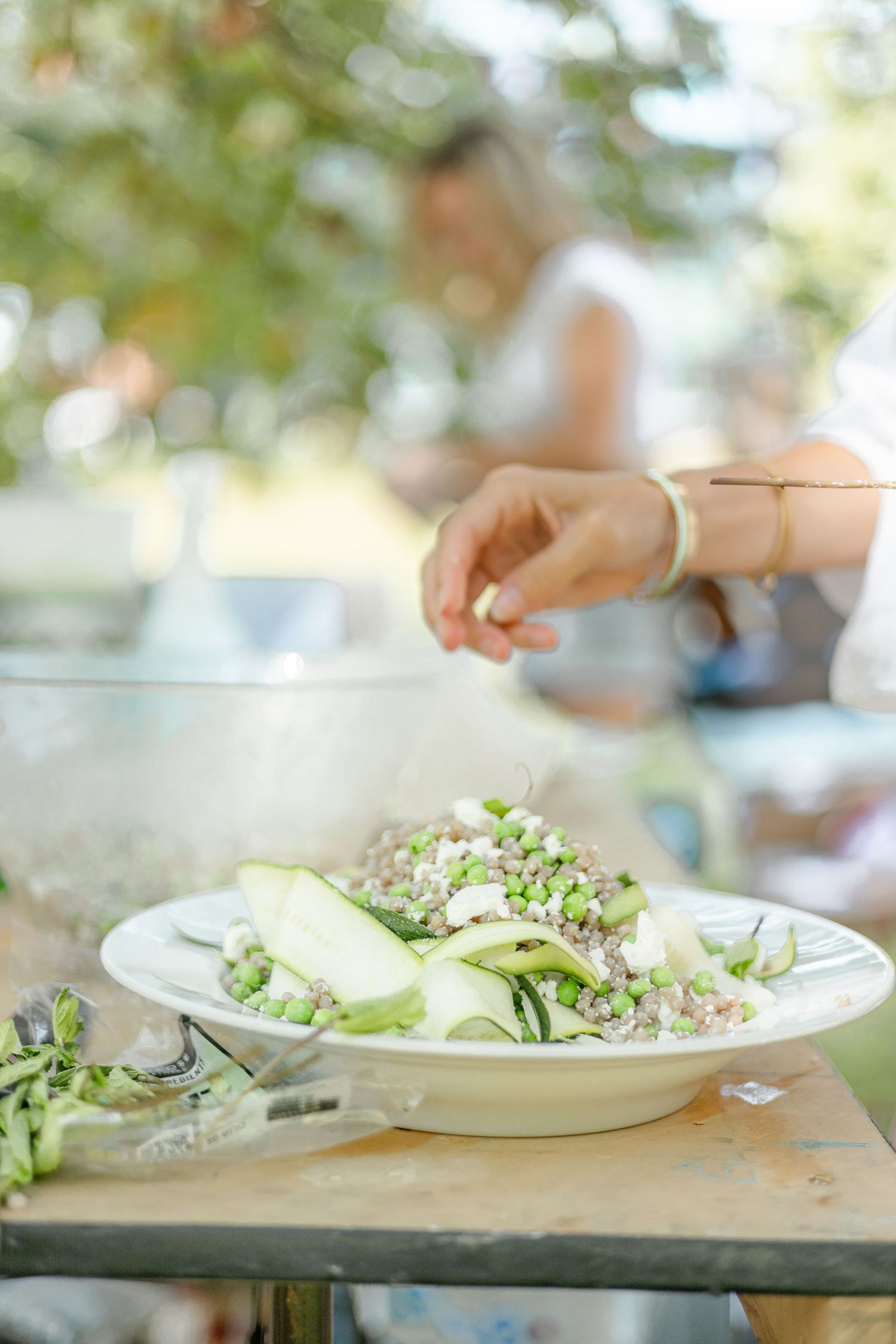 Fresh salad plates being prepared with delicate garnishes on a wooden surface.