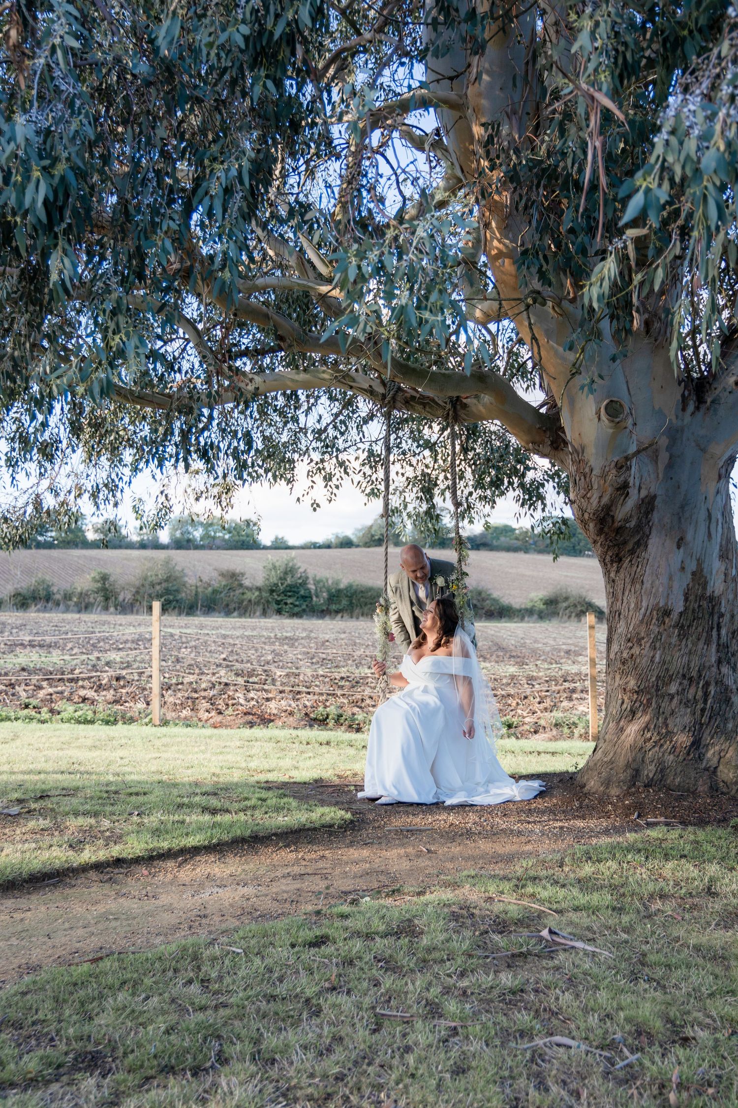 A white dress flows in the breeze beneath towering eucalyptus trees in a serene outdoor setting.