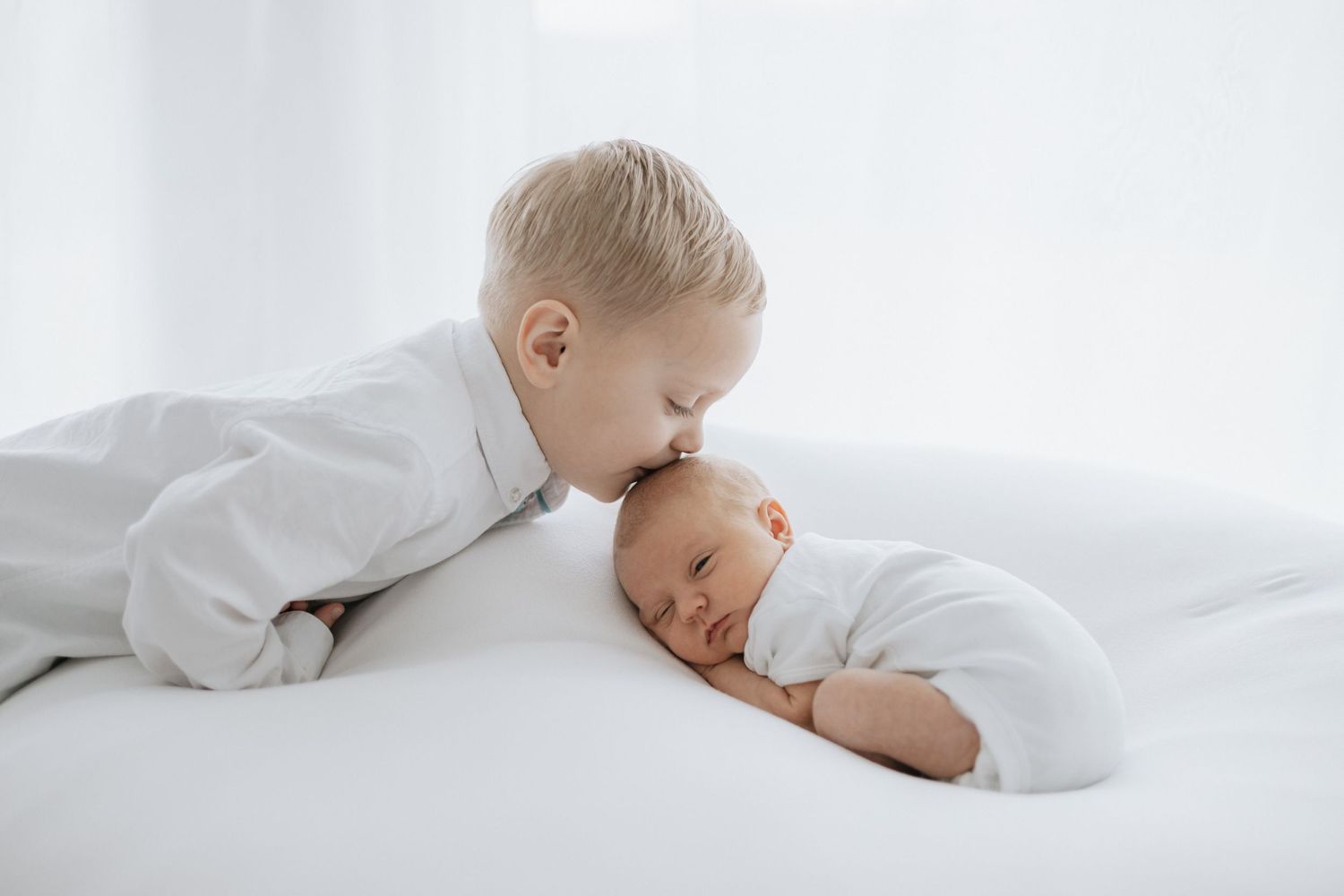Minimalist newborn photography series in white featuring gentle sleeping poses.