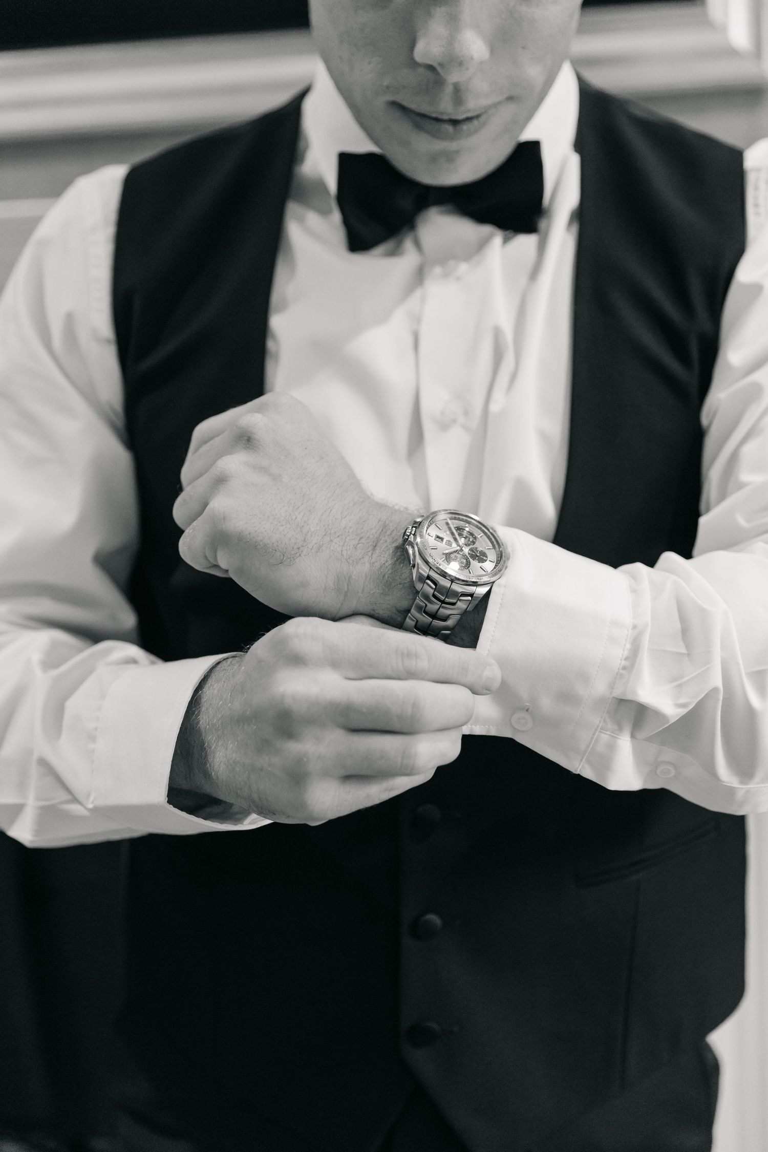 Close-up of formal attire with white dress shirt, black bow tie, and luxury watch.