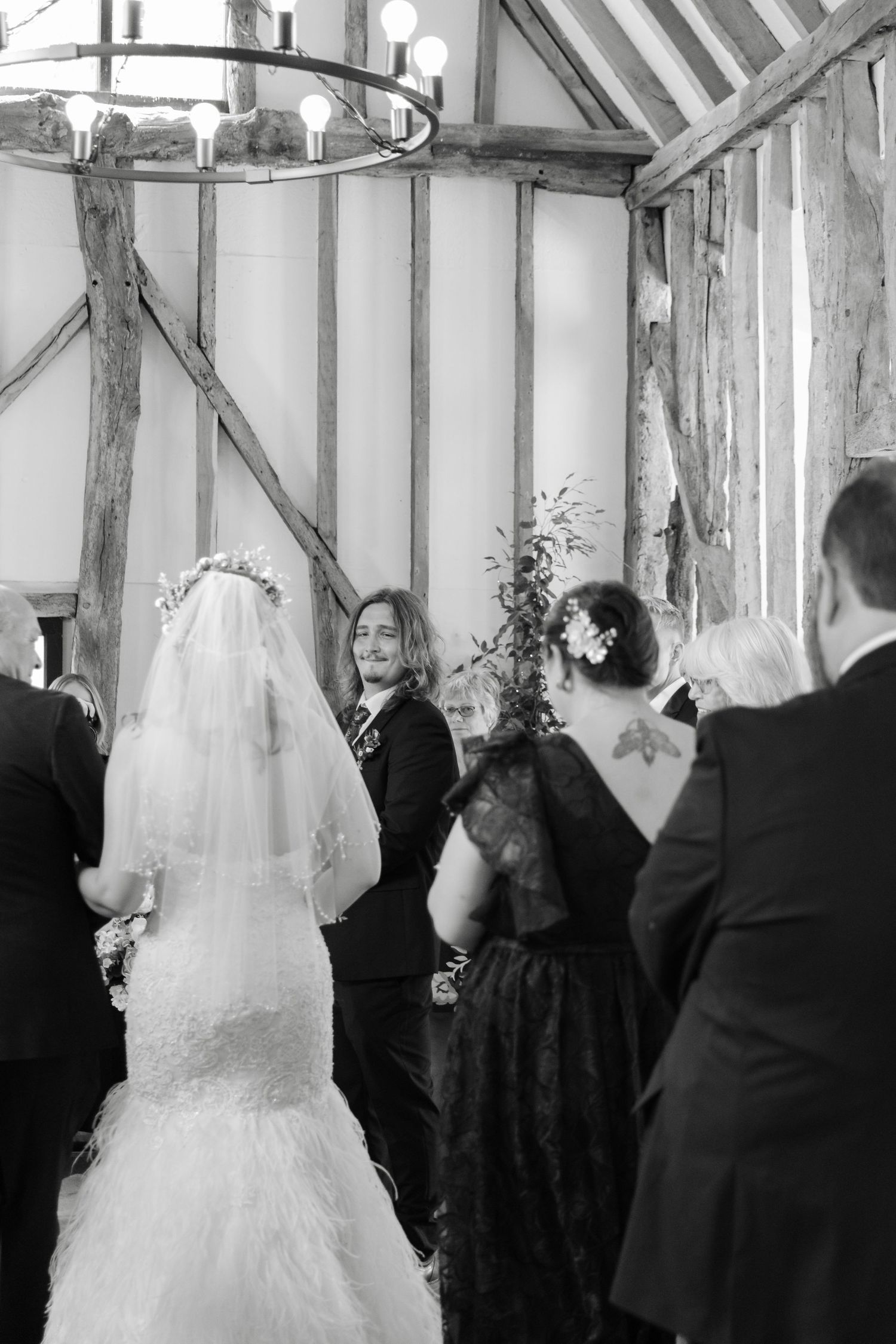 Black and white wedding ceremony photos in a rustic timber-framed venue with dramatic lighting.