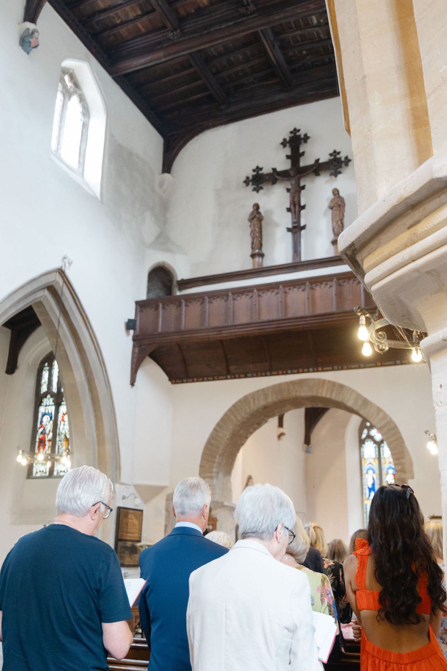 Interior view of a traditional church with wooden beams and stained glass windows during a service.