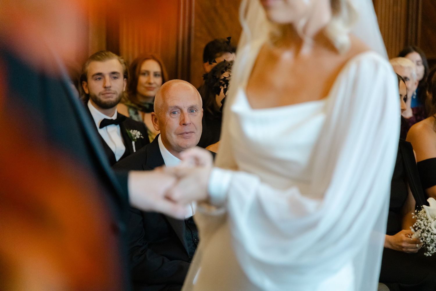 Wedding celebration scene with guests in formal attire at elegant venue.