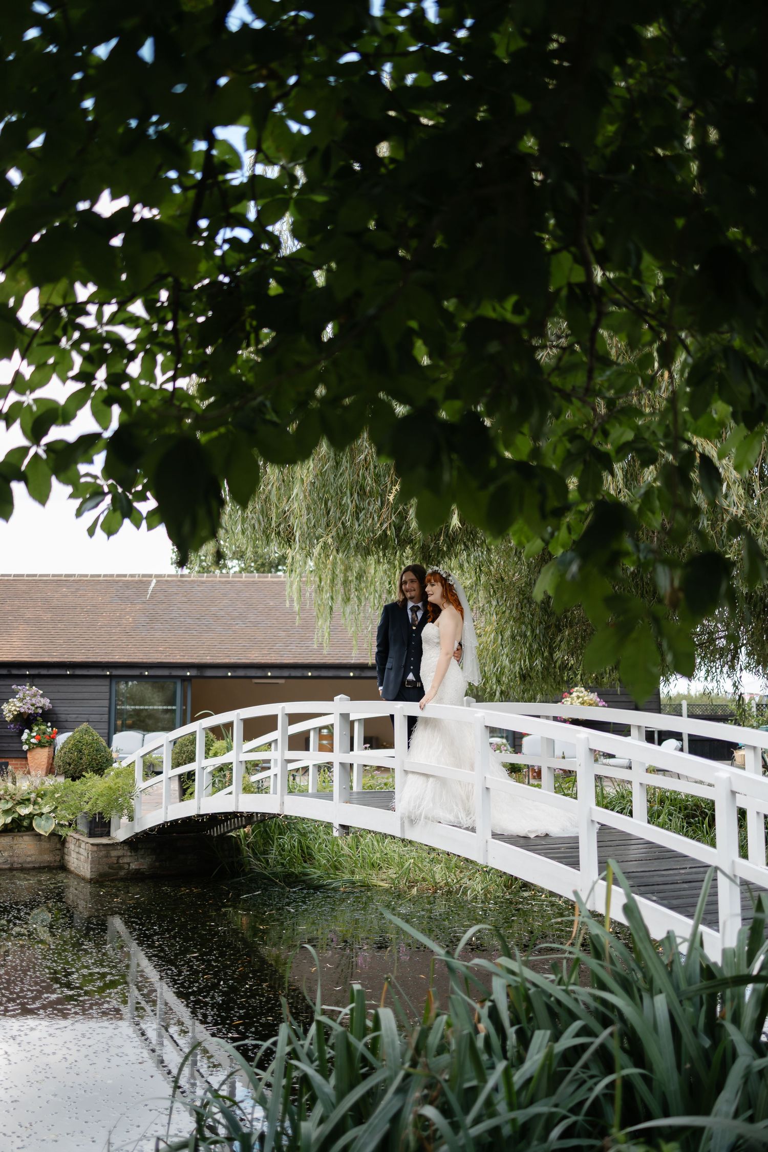 Black and white wedding photo of a couple exchanging looks outdoors.