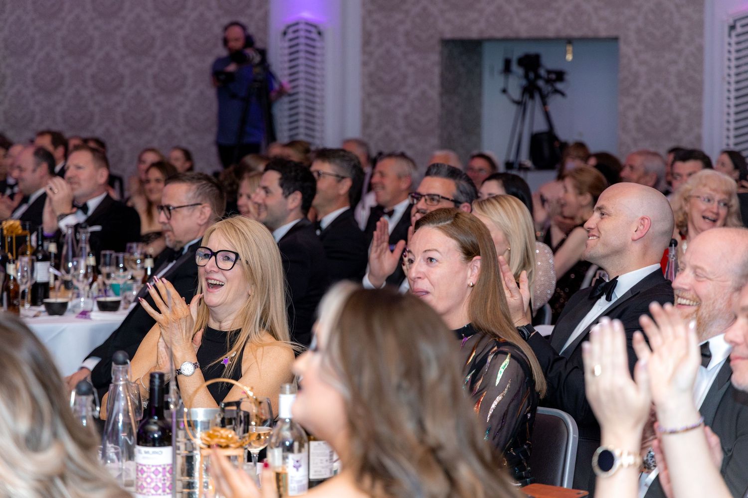 Audience members laughing and enjoying themselves at a formal dinner event.