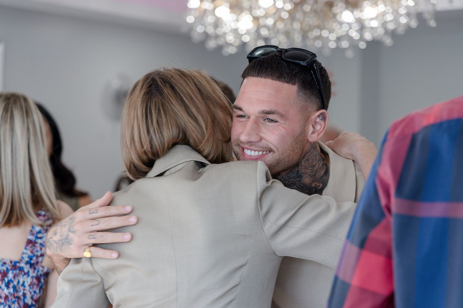 A warm embrace between two people at an indoor celebration.