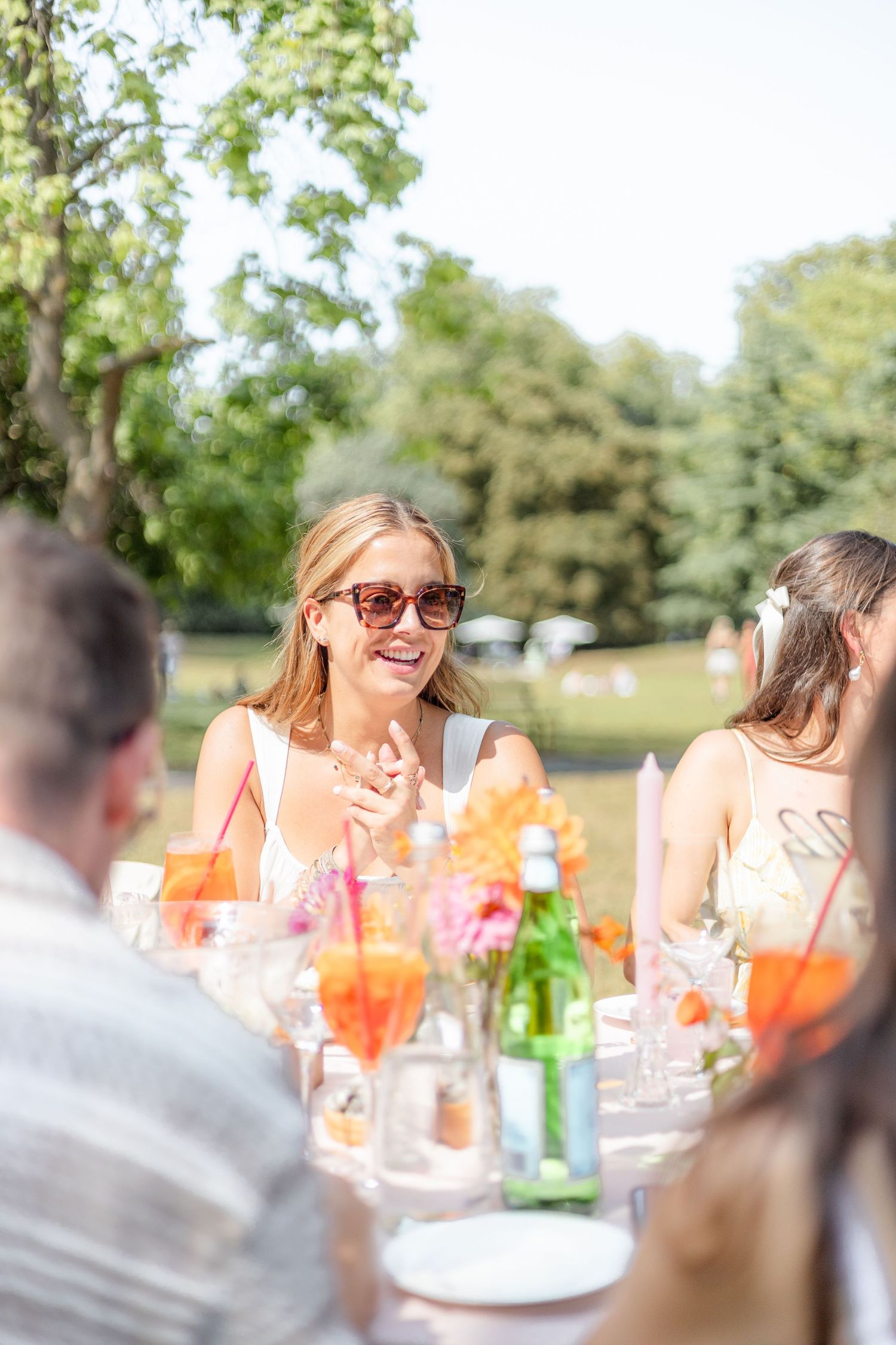 Summer outdoor party with guests enjoying drinks and conversation at a decorated table.