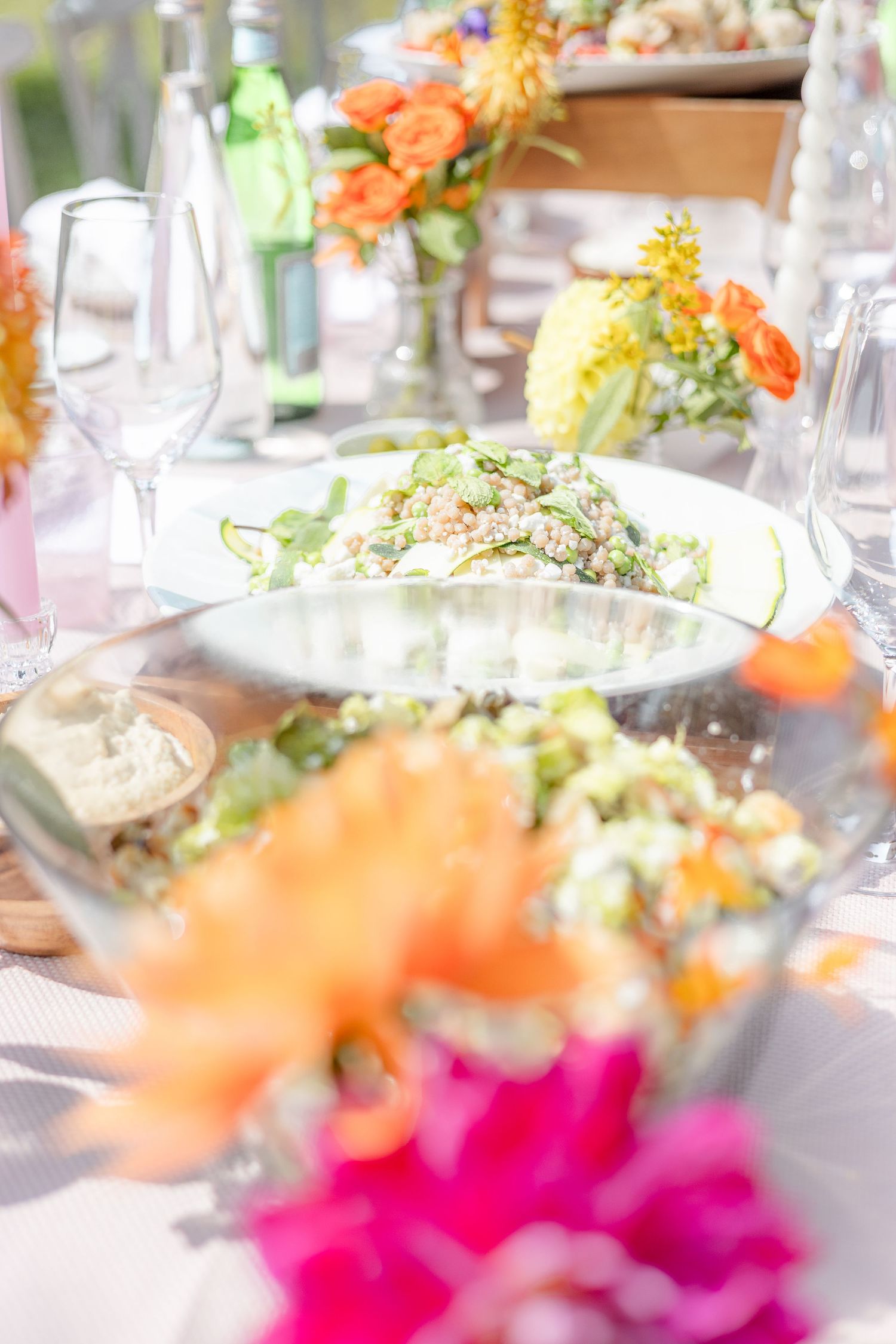Colorful floral centerpieces with orange and pink flowers decorate an elegant table setting.