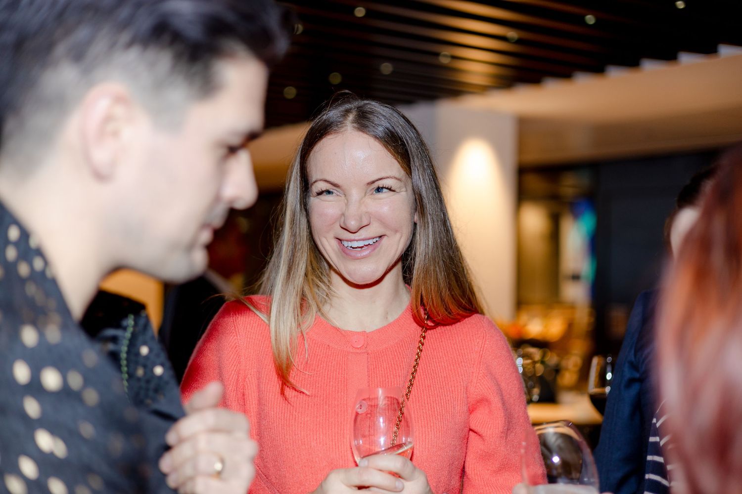 Partygoers smiling and laughing during an indoor social event.
